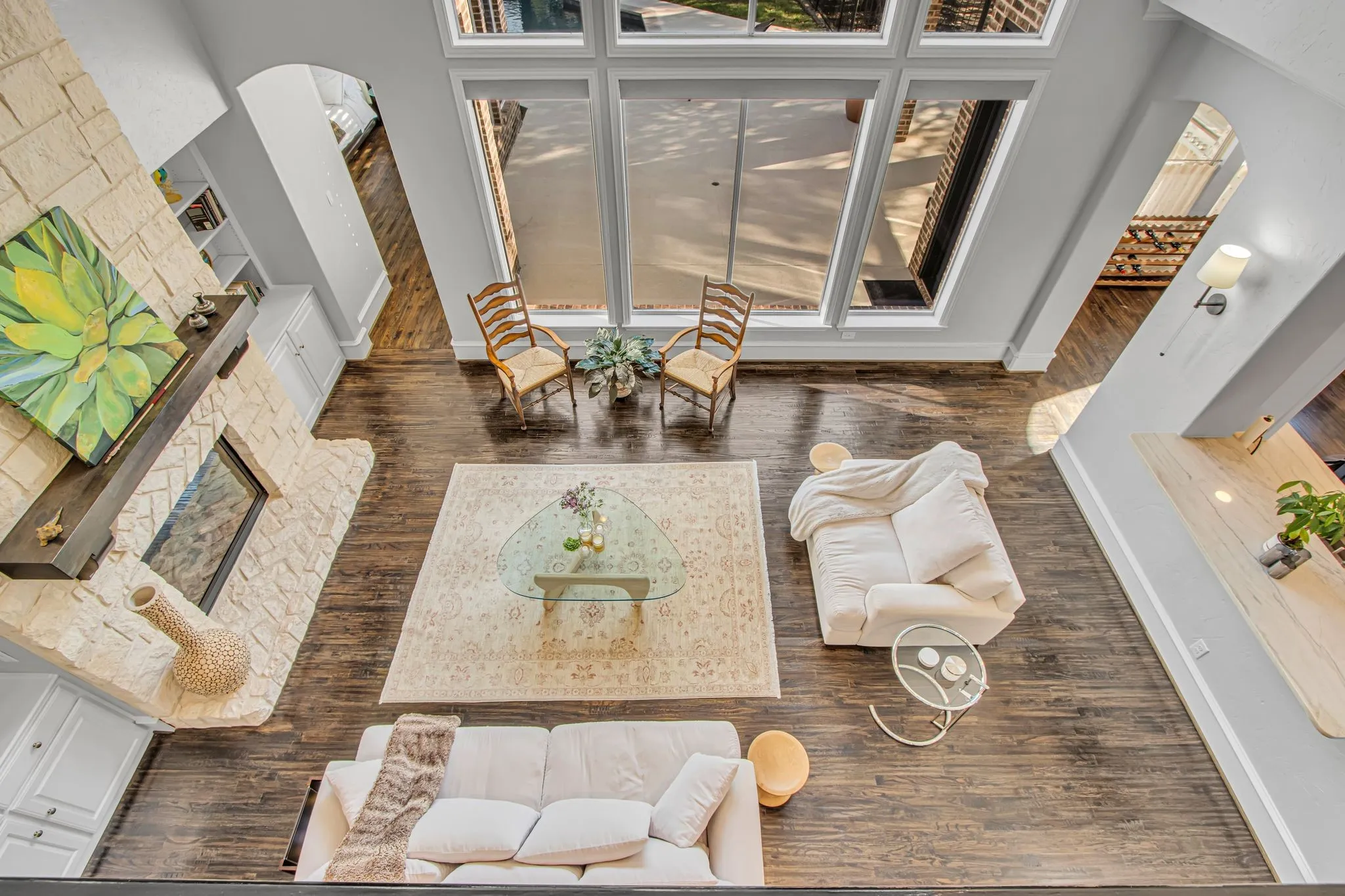Bright, open living spaces showcasing soaring ceilings, abundant natural light from expansive multi-panel windows, and warm wood-finish flooring throughout.