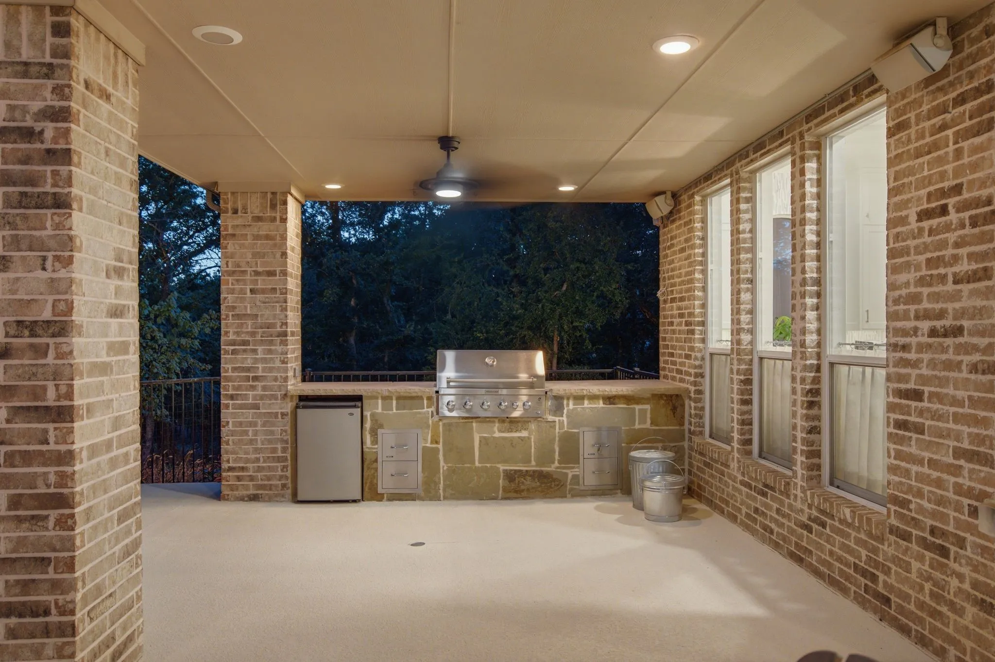 Covered outdoor patio featuring a built-in stone and brick outdoor kitchen with a grill and refrigerator