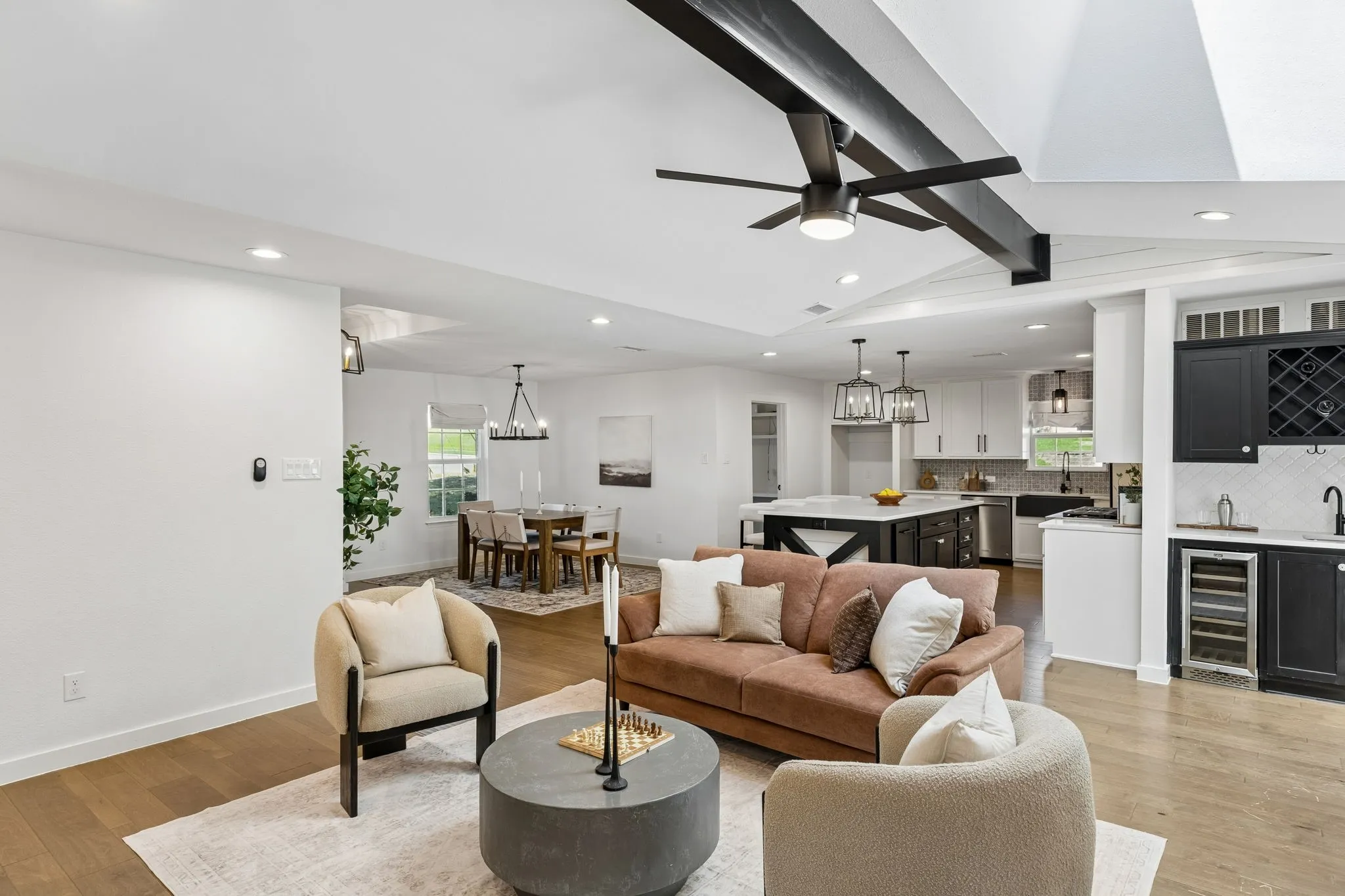 Open-concept living space featuring wood-finish flooring, recessed lighting, and exposed ceiling beams