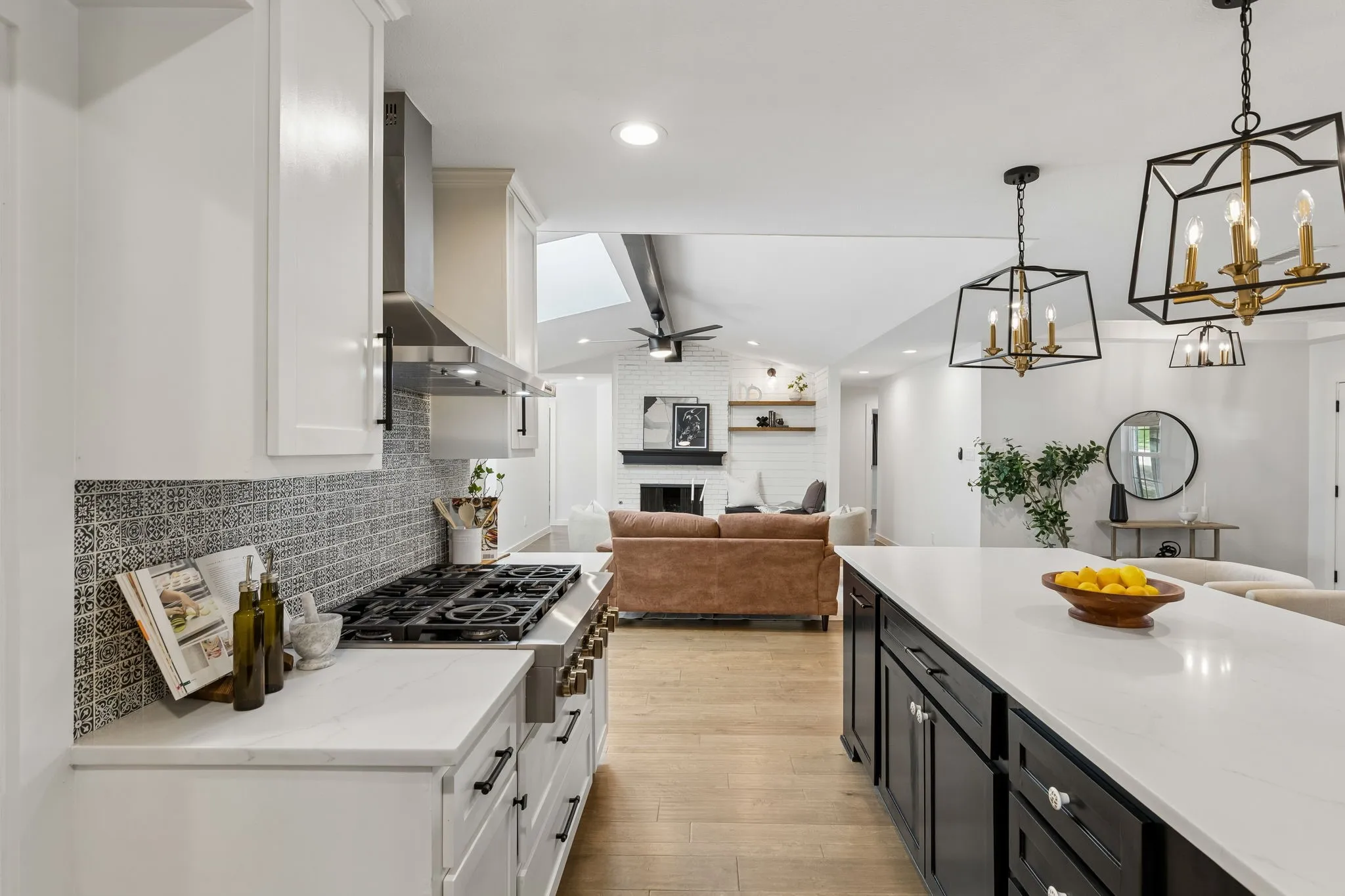 White kitchen cabinetry with a patterned tile backsplash, stainless steel range hood, and a gas range