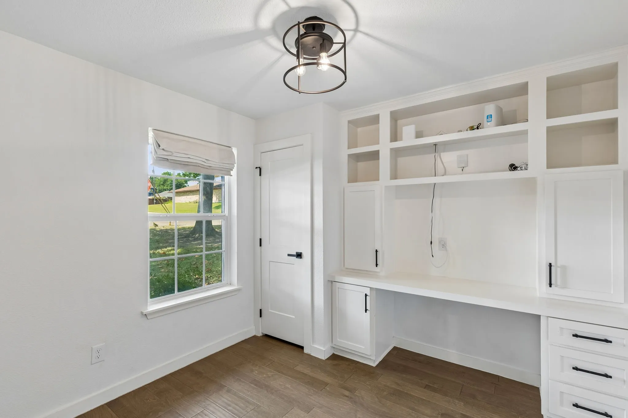 Built-in desk with cabinetry and shelving, wood-finish flooring, and a modern ceiling fixture