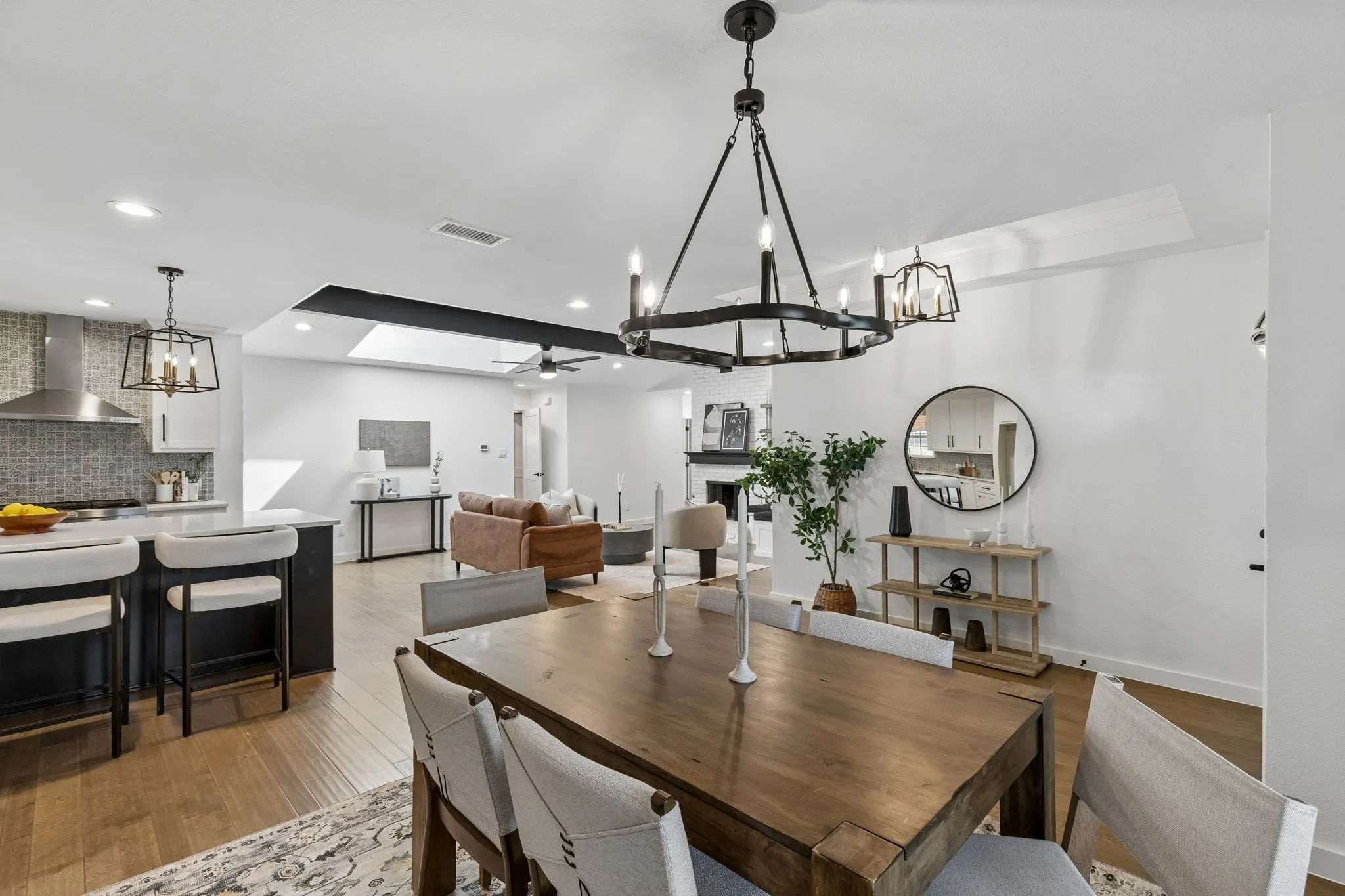 Open-concept interior featuring wood-finish flooring, a kitchen island with seating, pendant lighting, a dining area with a chandelier, and a living area with a fireplace