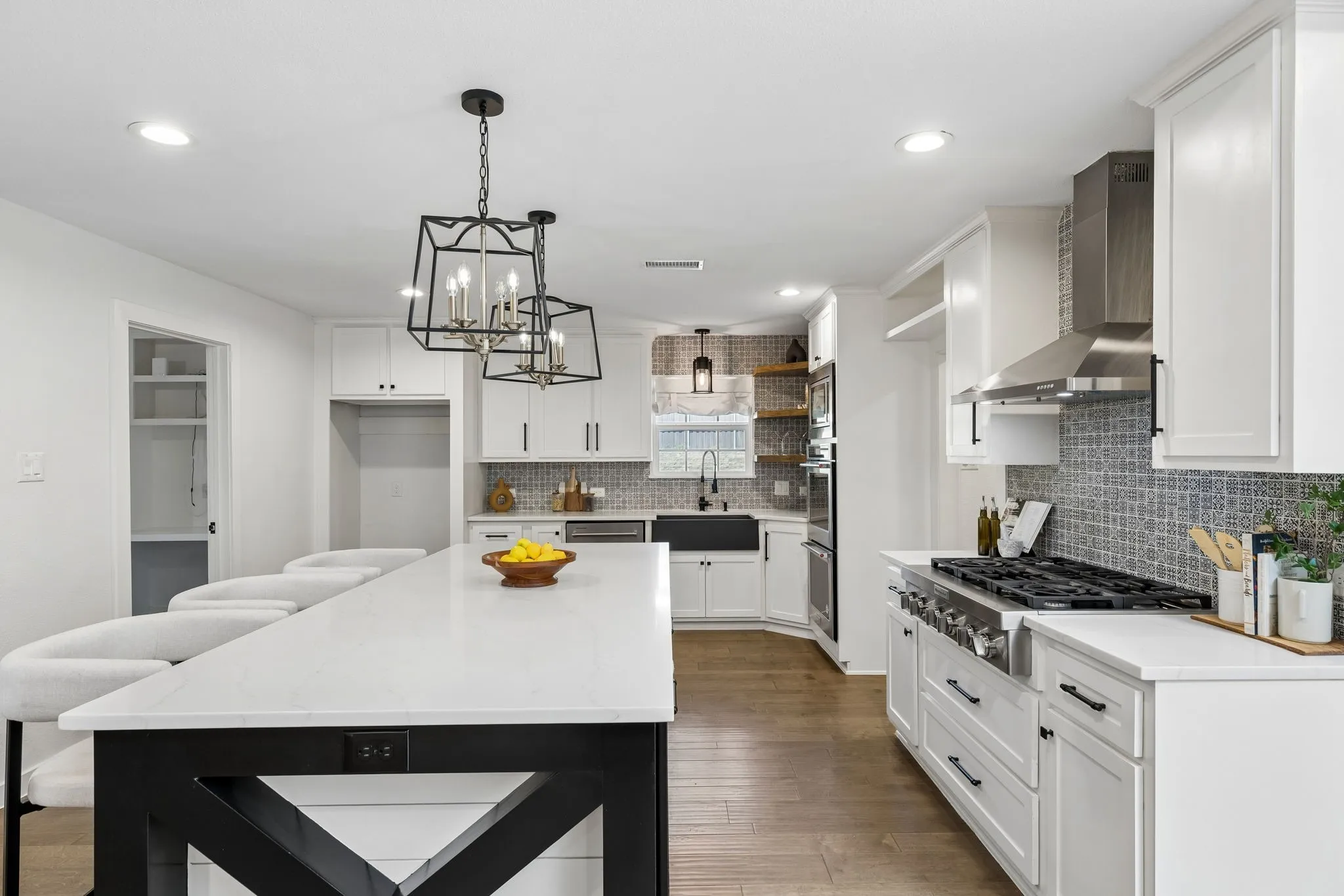 Spacious kitchen featuring white cabinetry, a large center island with a white countertop, wood-finish flooring, a stainless steel range hood, and a dark apron-front sink