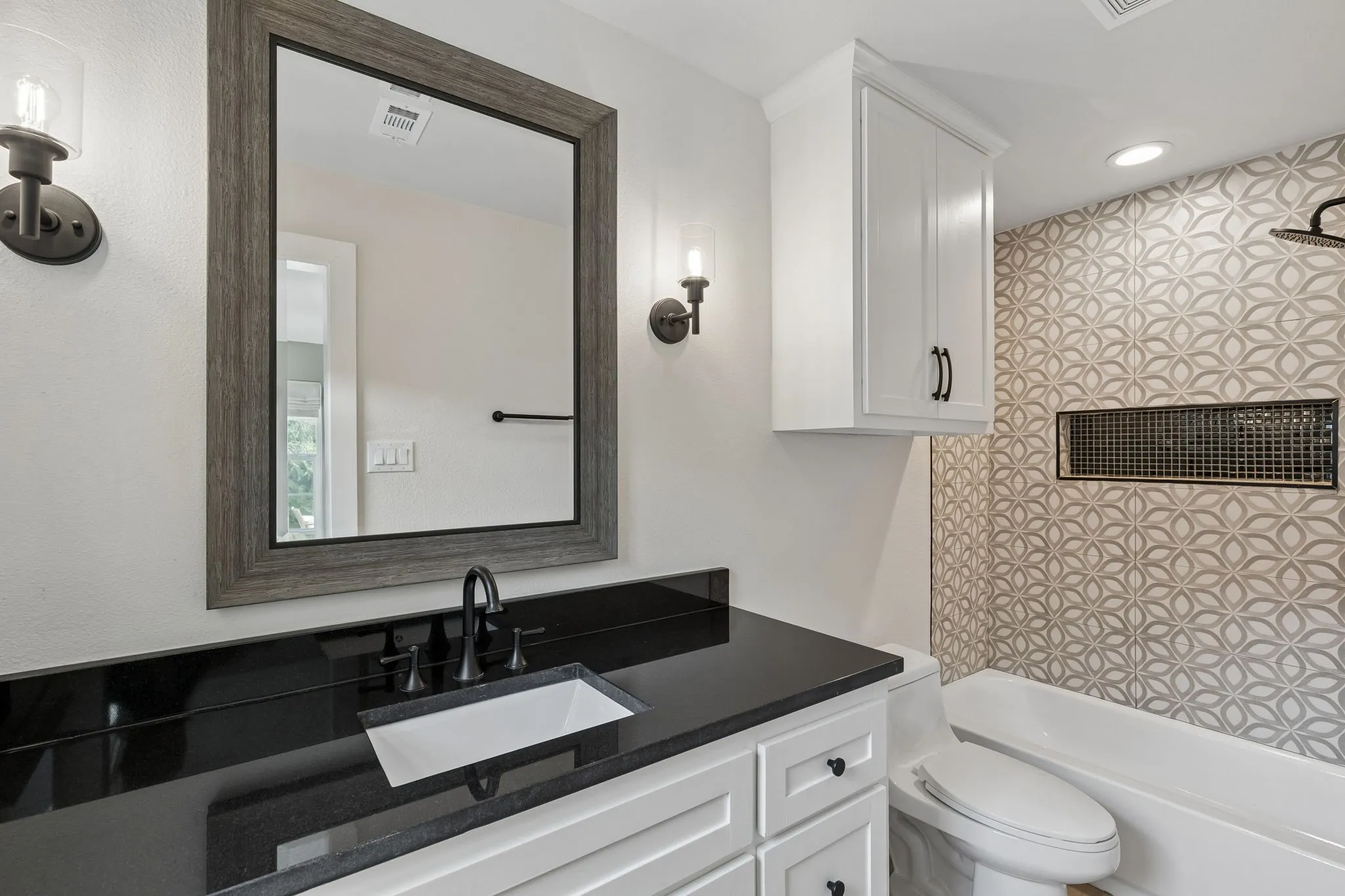White vanity with black countertop, undermount sink, and black faucet