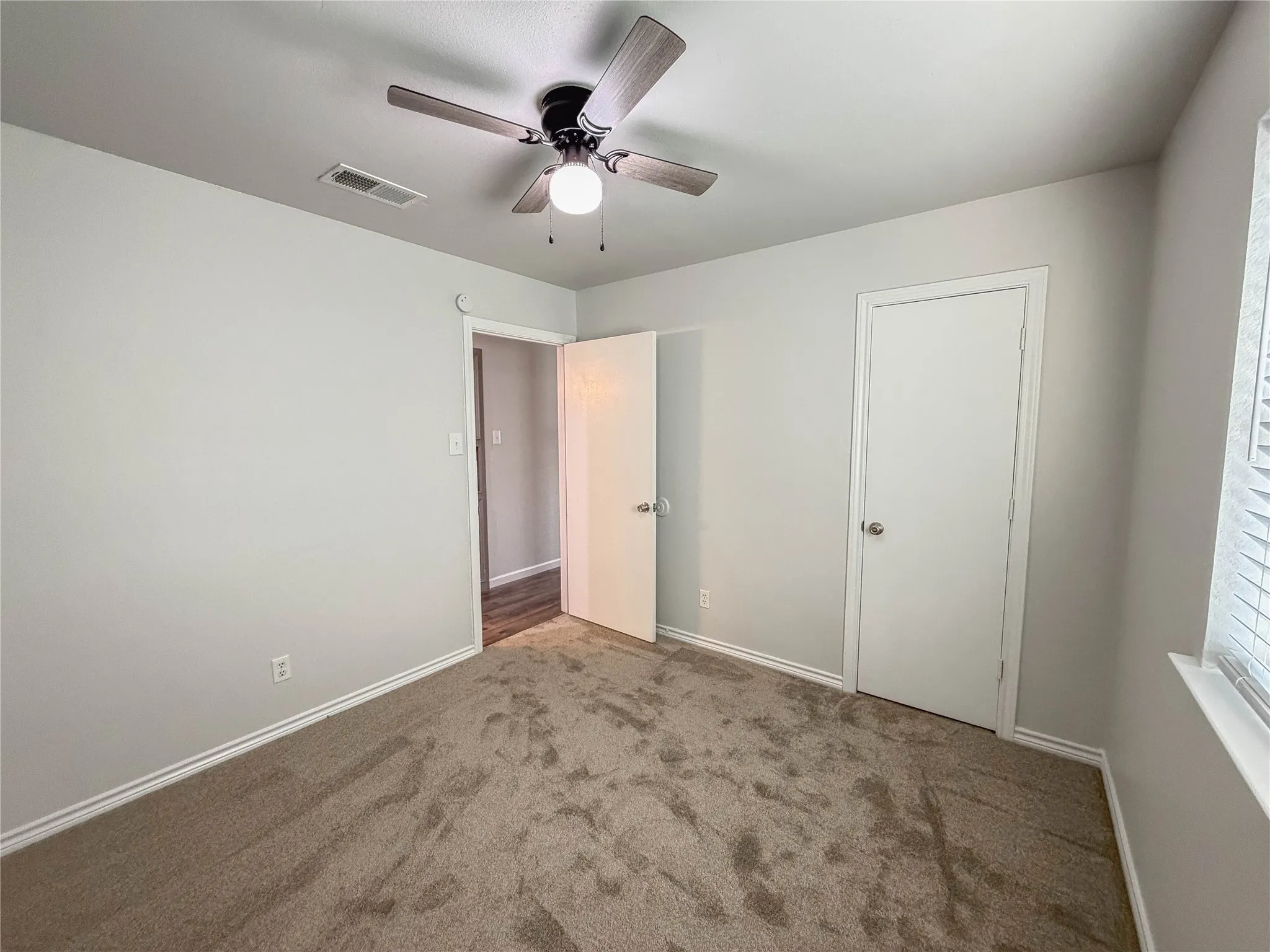 Plush carpet flooring, ceiling fan with integrated lighting, window with blinds, and white trim