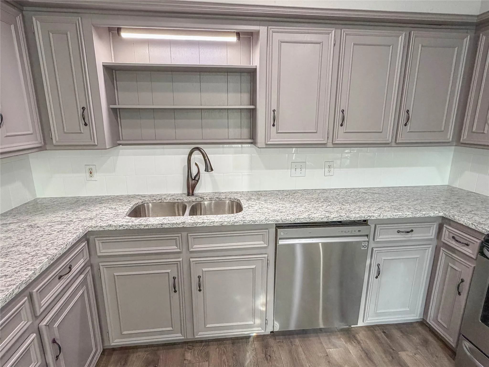 Granite countertops, dual basin sink, stainless steel dishwasher, light gray cabinetry, and subway tile backsplash