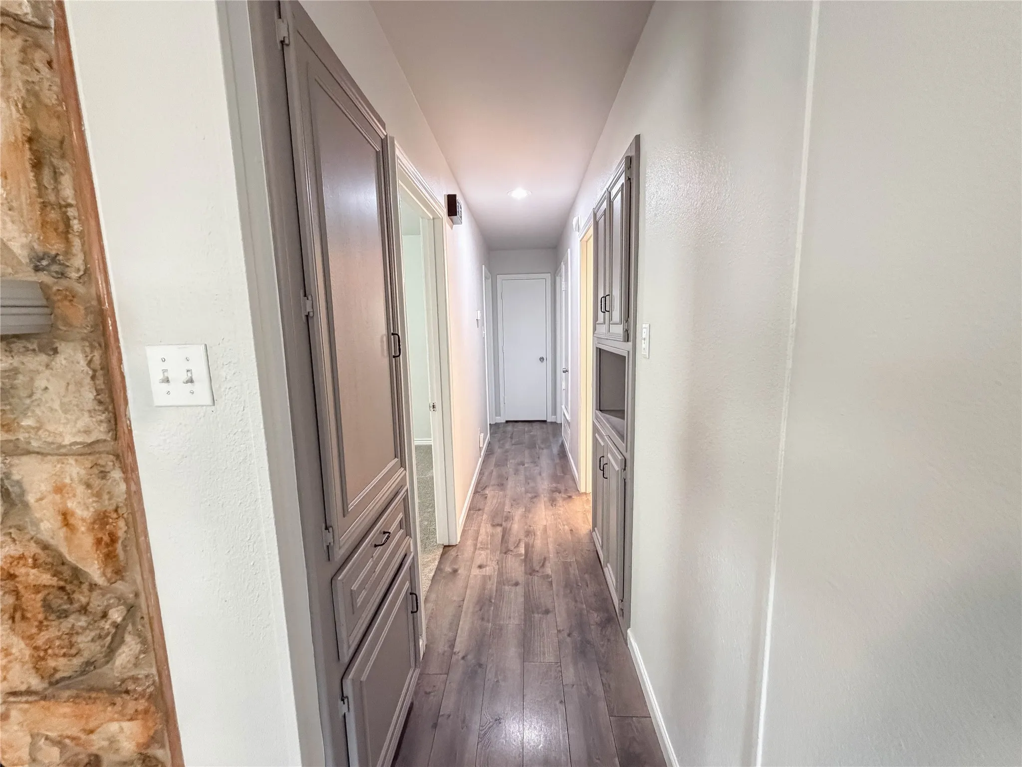 Hallway with wood-finish flooring, recessed lighting, and built-in cabinetry
