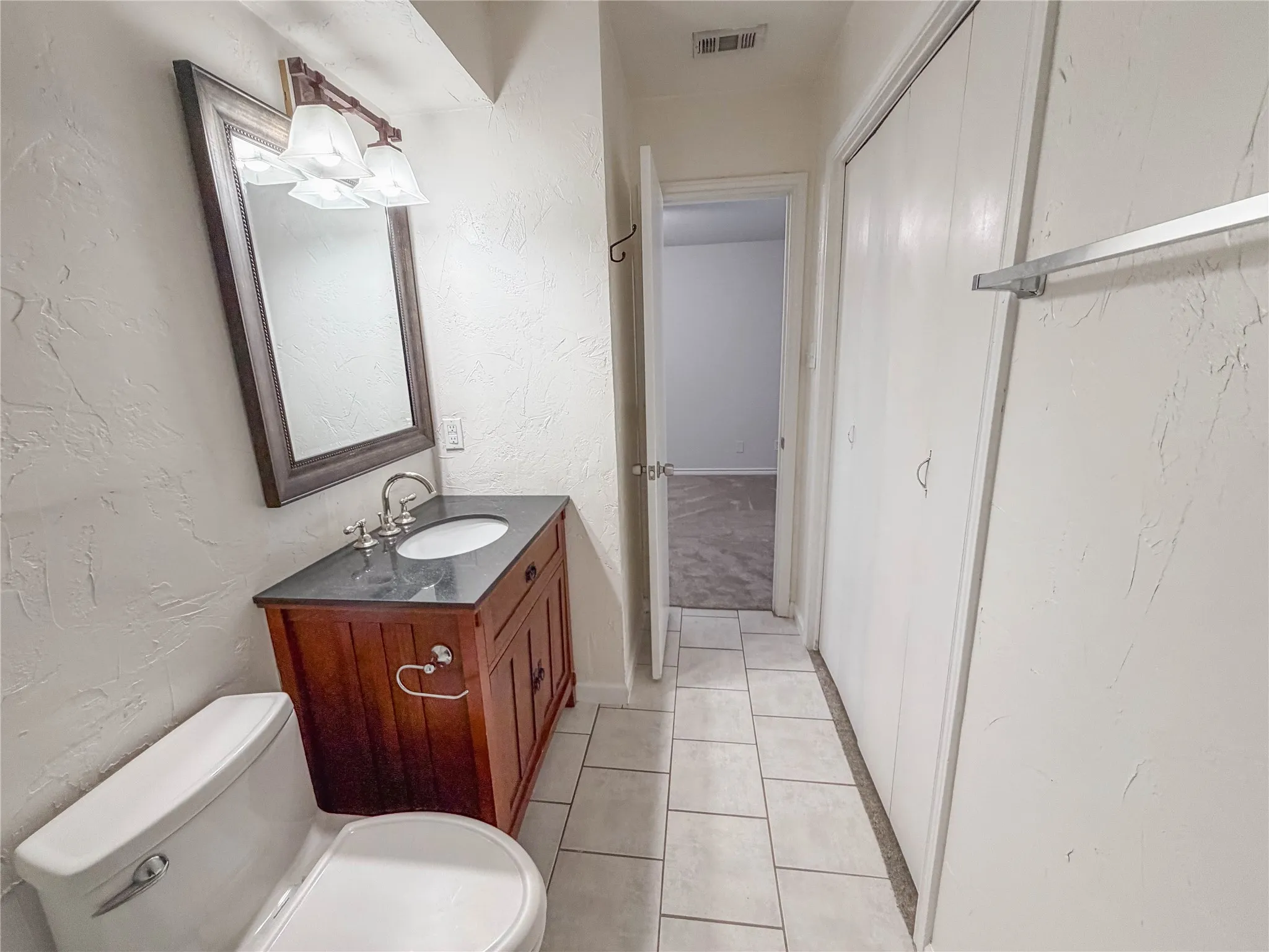 Bathroom vanity with dark wood-finish cabinetry, a dark countertop, and an undermount sink