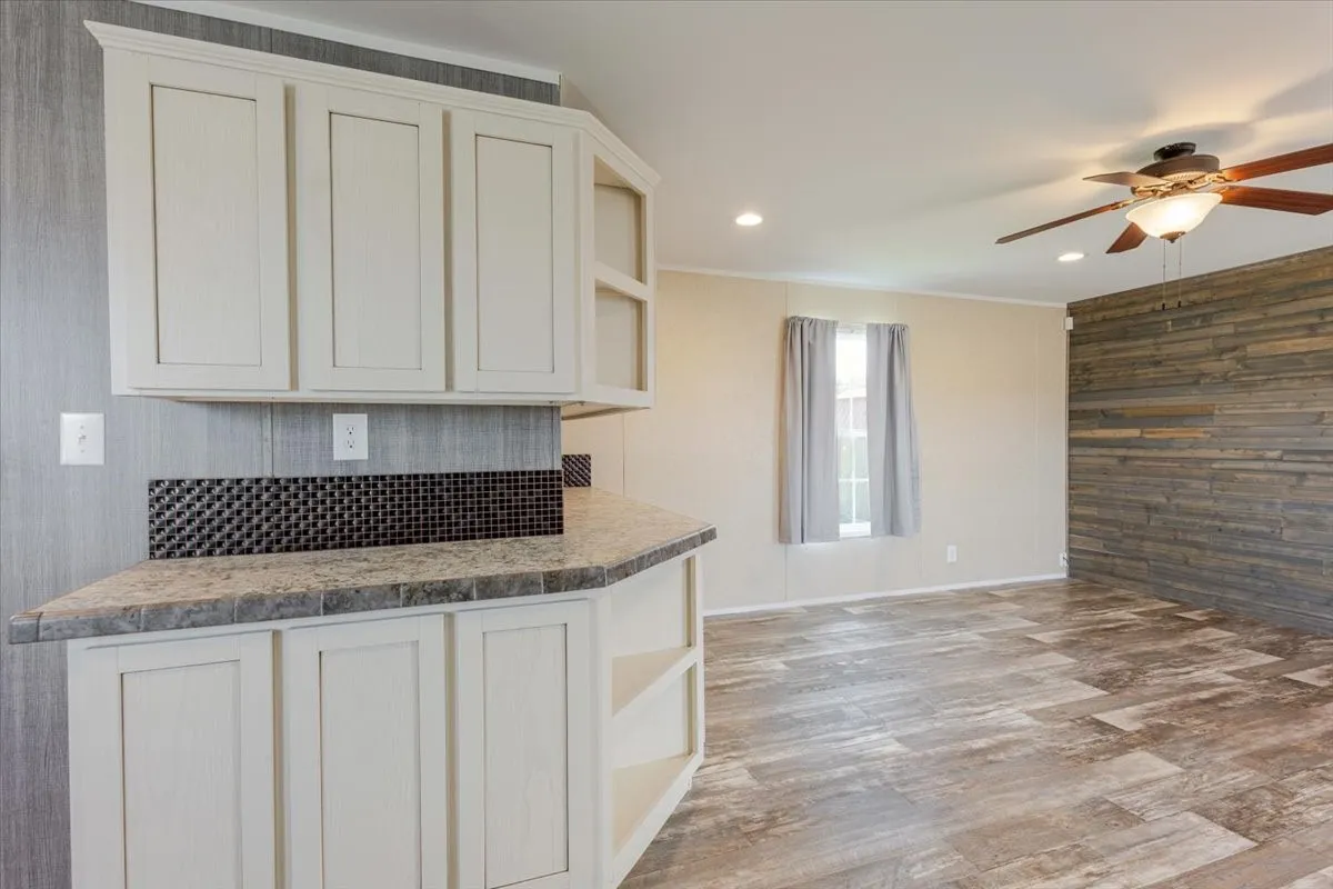 Kitchen pass-through featuring light-toned cabinetry, a mosaic tile backsplash, and a countertop with integrated edge tiling