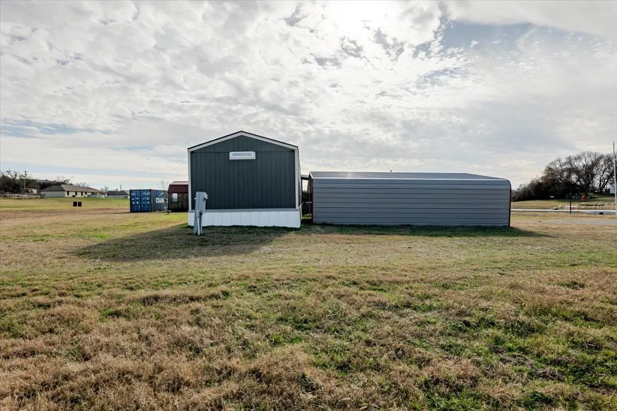 End of house showing carport, Convex and wooden work shop with electricity.