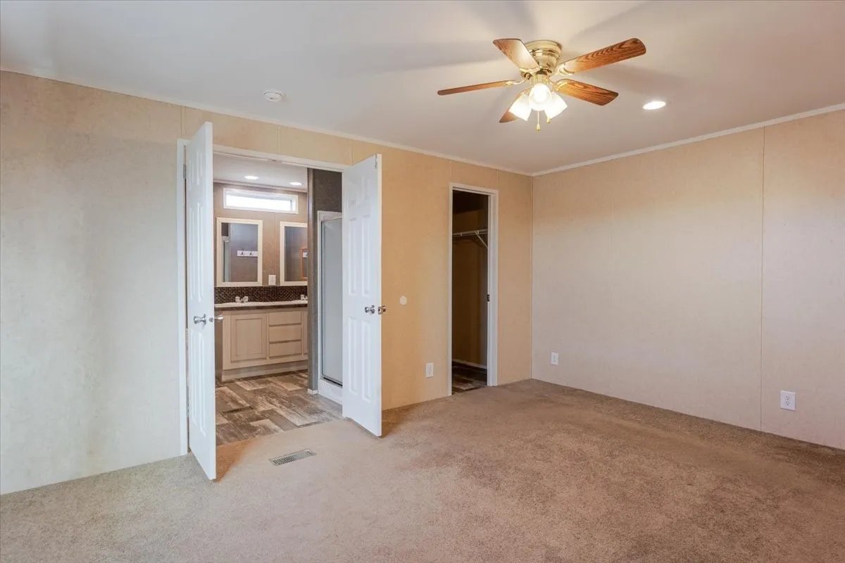 Carpeted room featuring a ceiling fan with integrated lighting, recessed lighting, and a doorway to a walk-in closet
