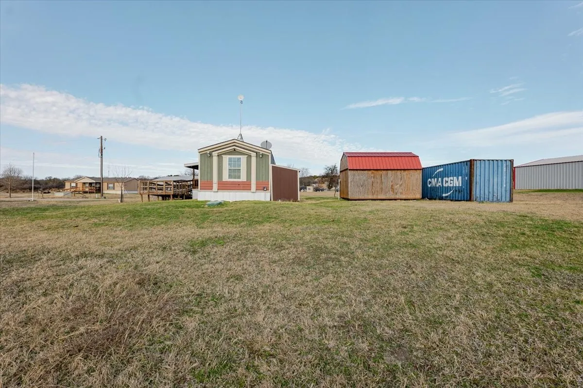 Manufactured home with gray siding and white trim, featuring a raised wooden deck and storage units.