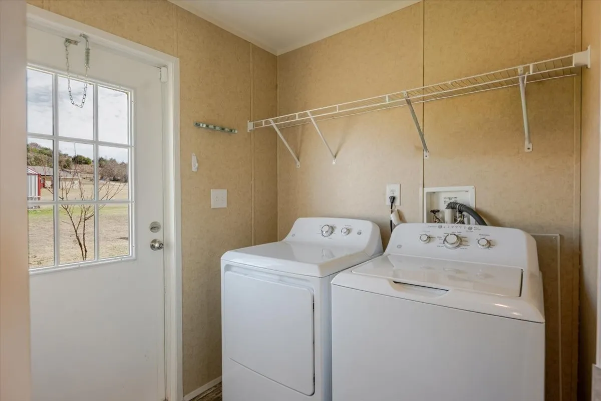 Utility room featuring wall-mounted wire shelving, wall-finish flooring, and a white paneled door with windowpanes.  Washer and dryer do not convey.