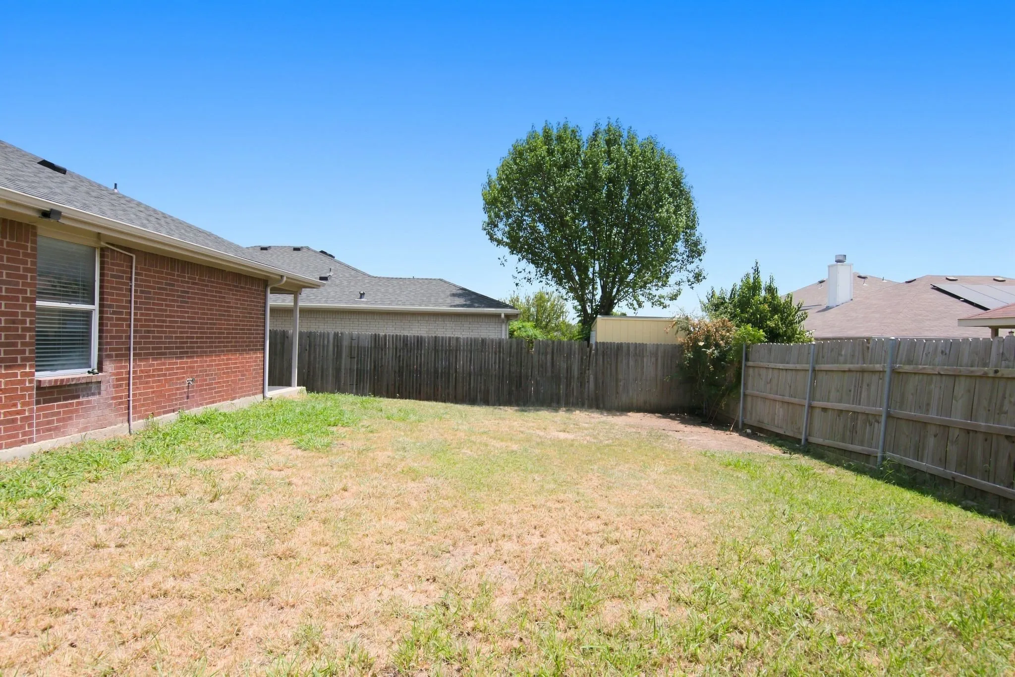 Private backyard featuring a wood privacy fence and mature tree