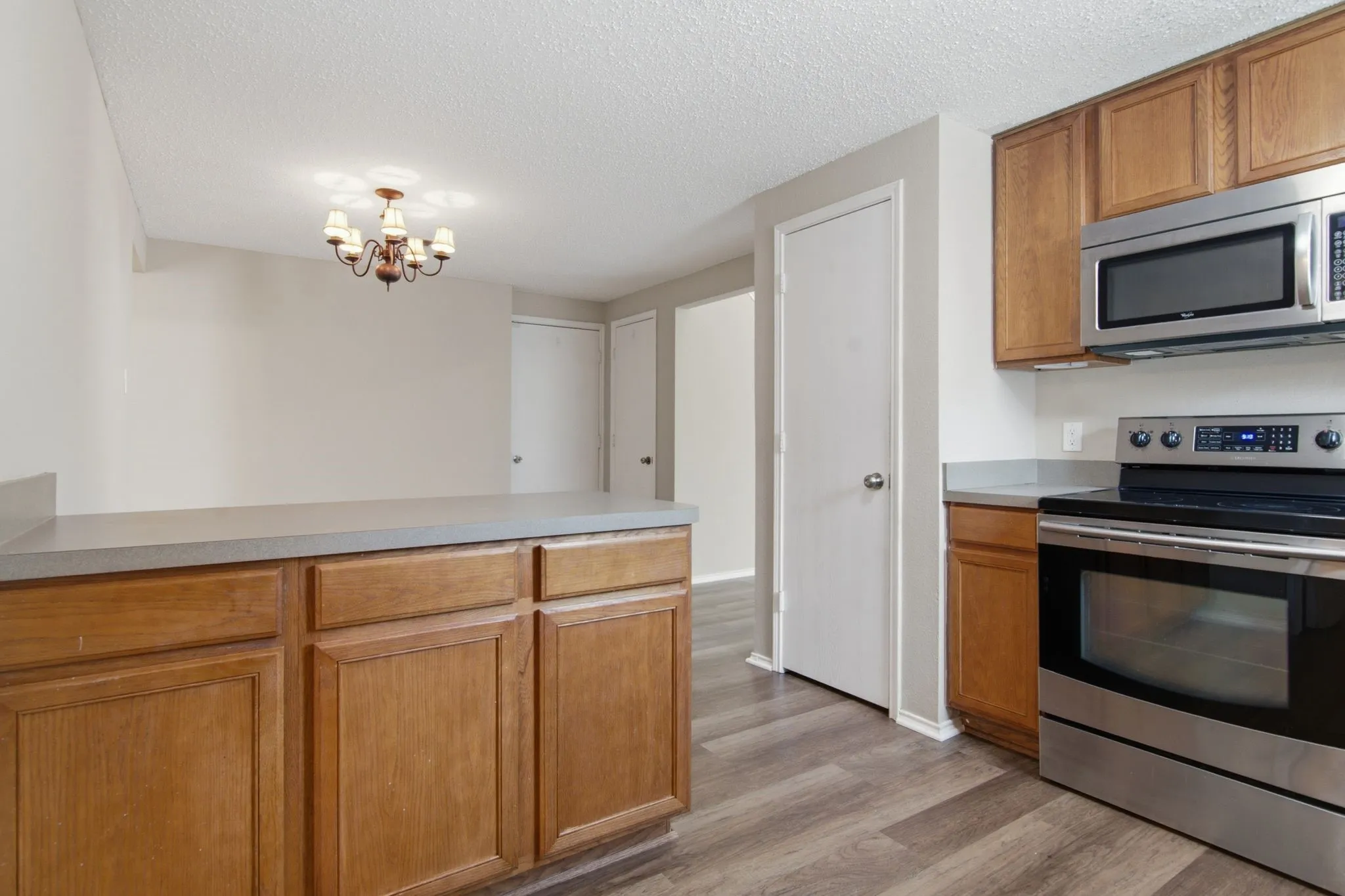 Kitchen featuring wood-finish flooring, stainless steel appliances, wood cabinetry, and grey countertops