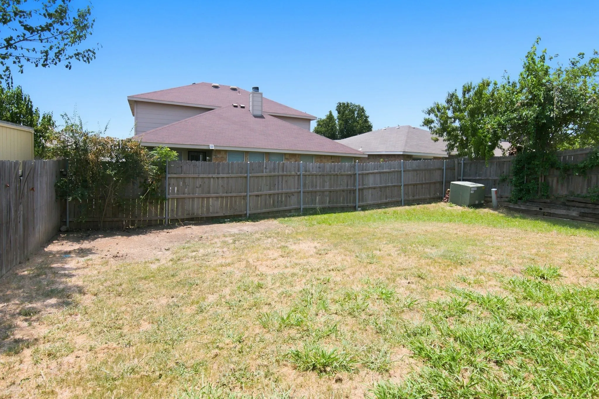 Expansive backyard enclosed by a wood privacy fence