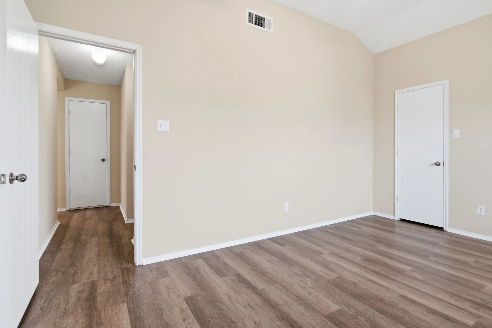 Vaulted ceiling with a recessed vent, wood-finish flooring, and neutral wall paint Secondary Bedroom Upstairs
