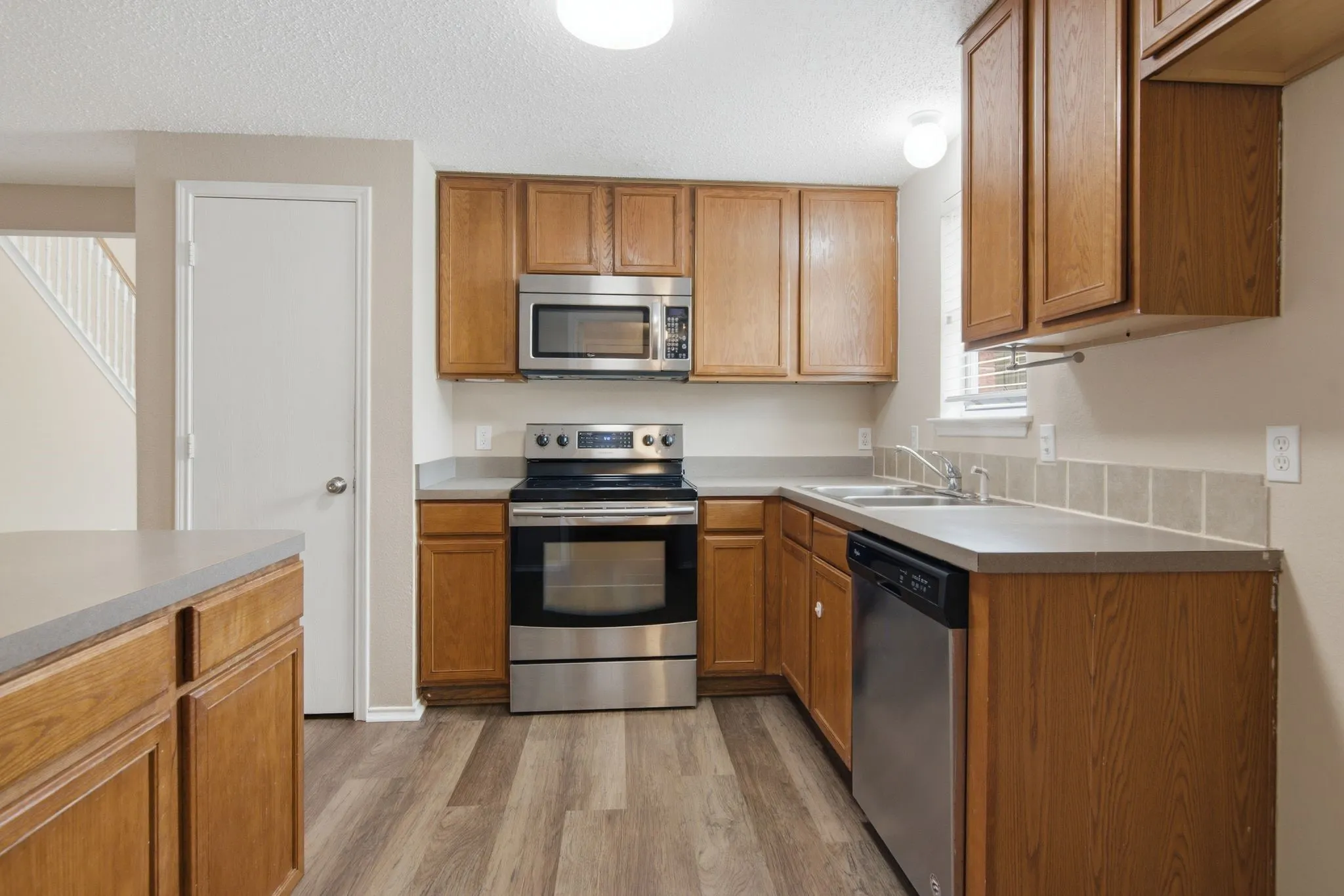 Kitchen featuring wood-finish cabinetry, stainless steel appliances, laminate countertops, and wood-finish flooring