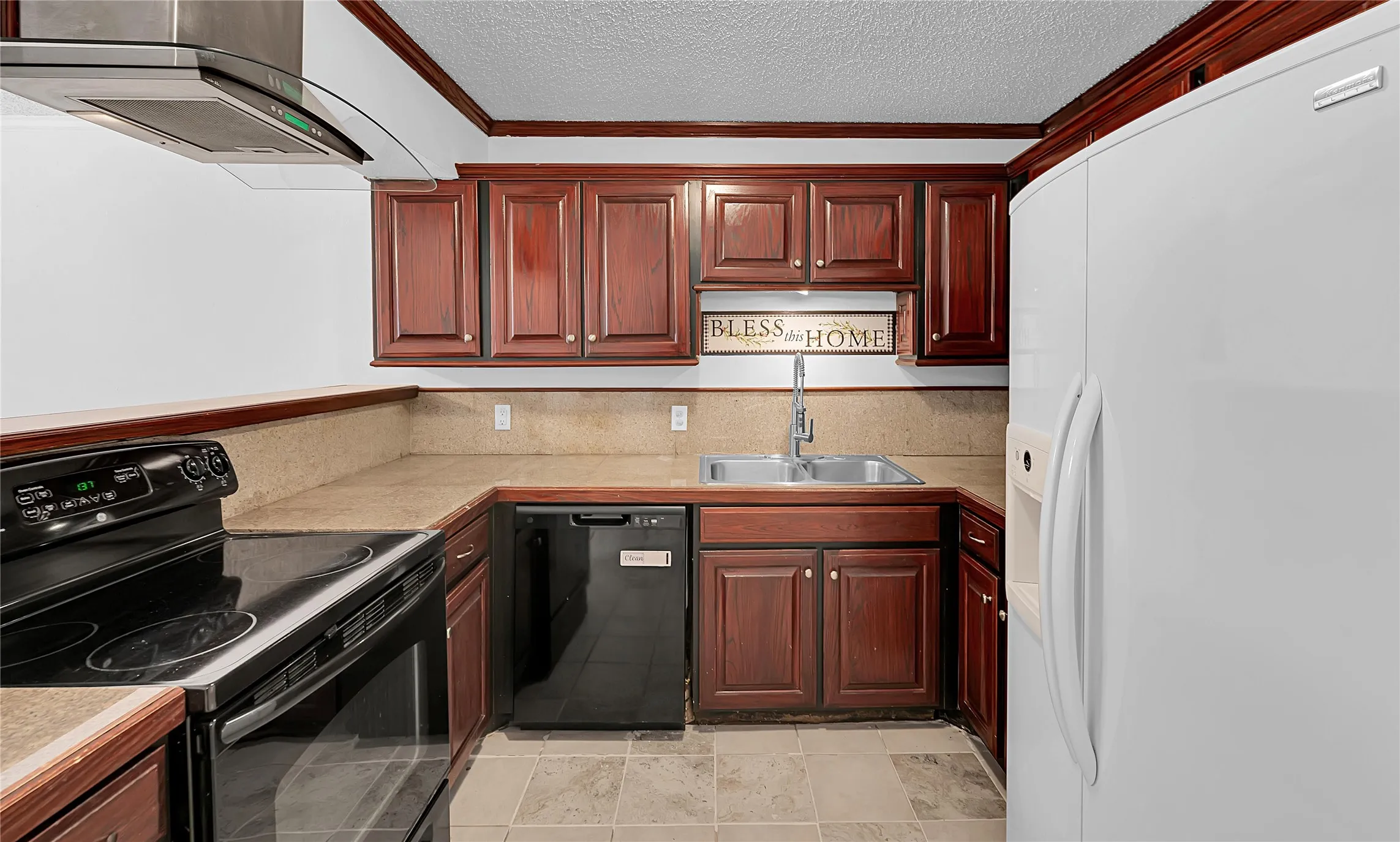 U-shaped kitchen with wood cabinetry, tile flooring, and integrated stainless steel sink