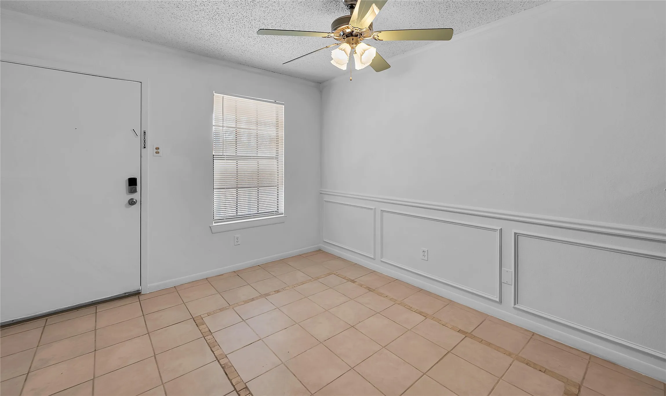 Tile flooring throughout, decorative wainscoting, and an overhead ceiling fan with integrated lighting