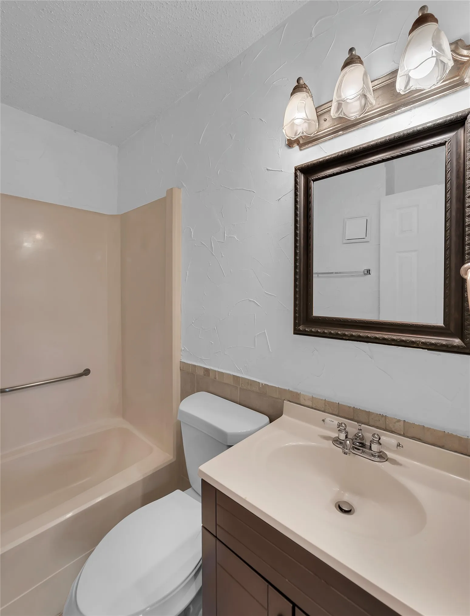 Vanity with integral sink, chrome faucet, and dark wood-finish cabinetry