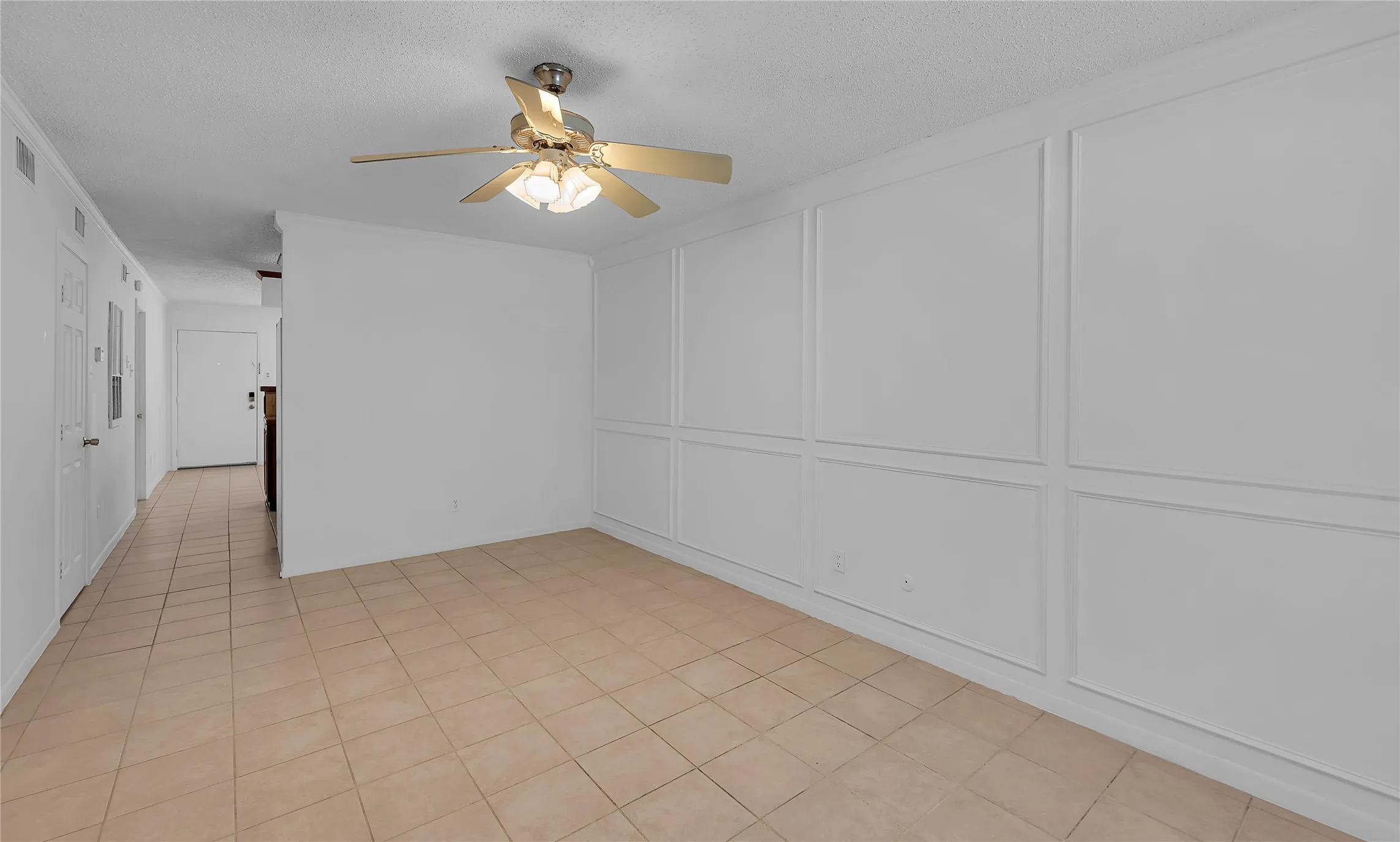 Panel molding accent wall, ceiling fan with integrated lighting, tile flooring, and a white interior door