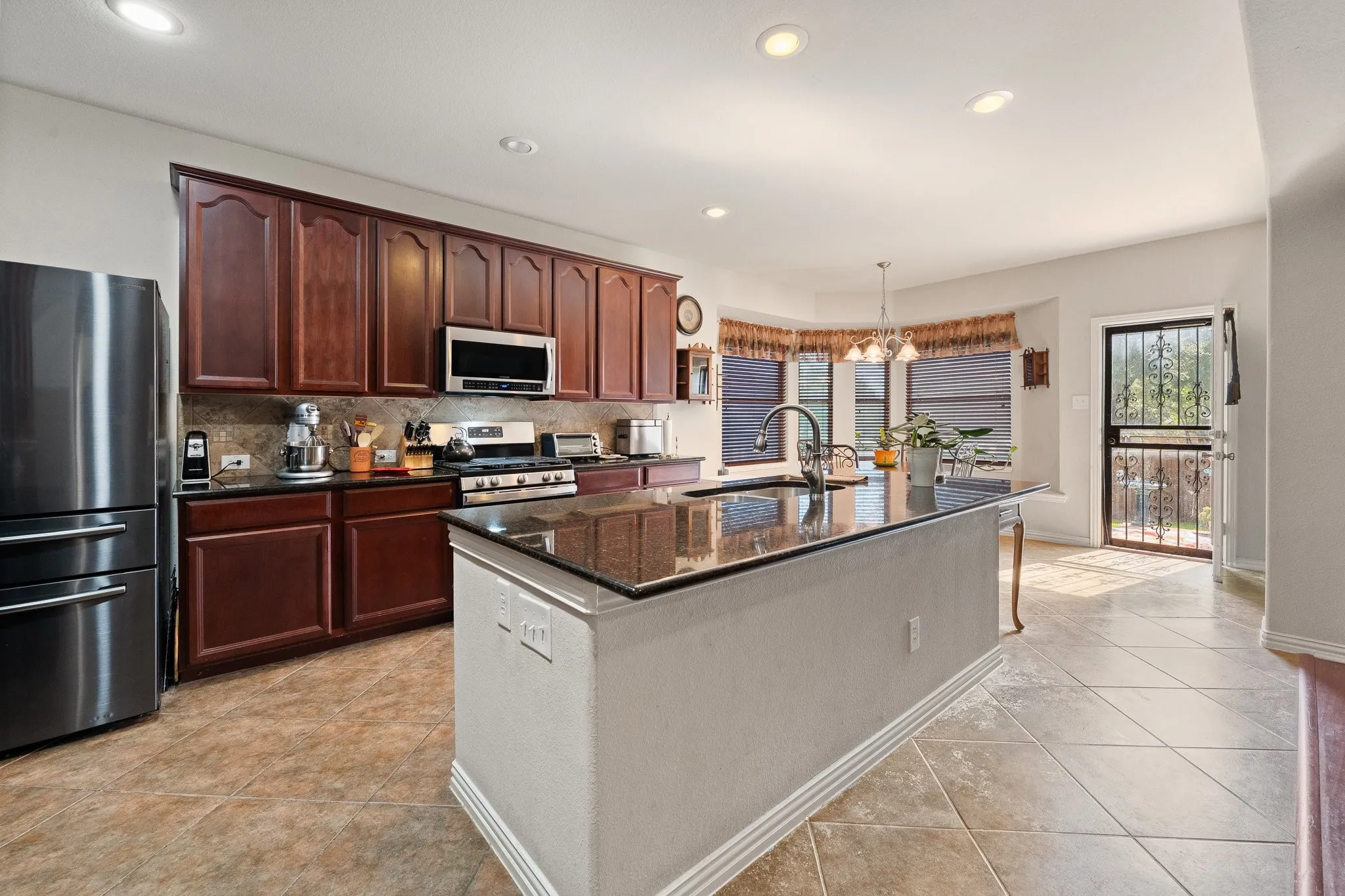 Kitchen featuring a Large ISLAND, granite countertops, wood cabinetry, GAS Range, stainless steel appliances, and tile flooring