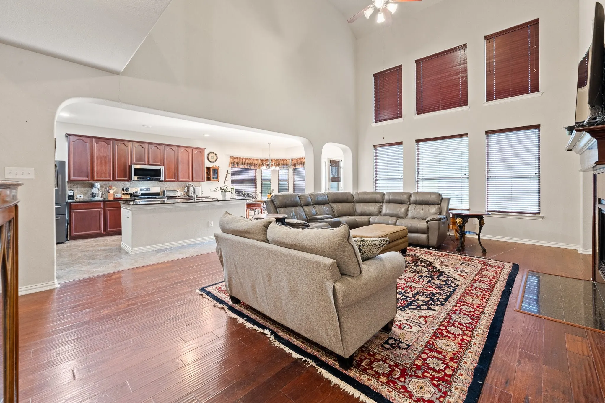 Open Concept Family Room: wood flooring, multiple windows with blinds, Fireplace, and an arched entryway to the kitchen and breakfast room.