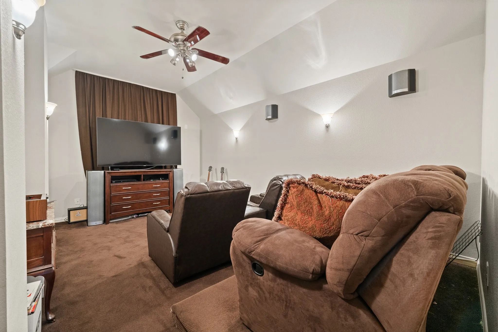 Upstairs MEDIA Room features tiered seating, ceiling fan, sconce lighting, and carpeting.  Tiered Seating and TV CONVEY!  OPENS to Upstairs Balcony...