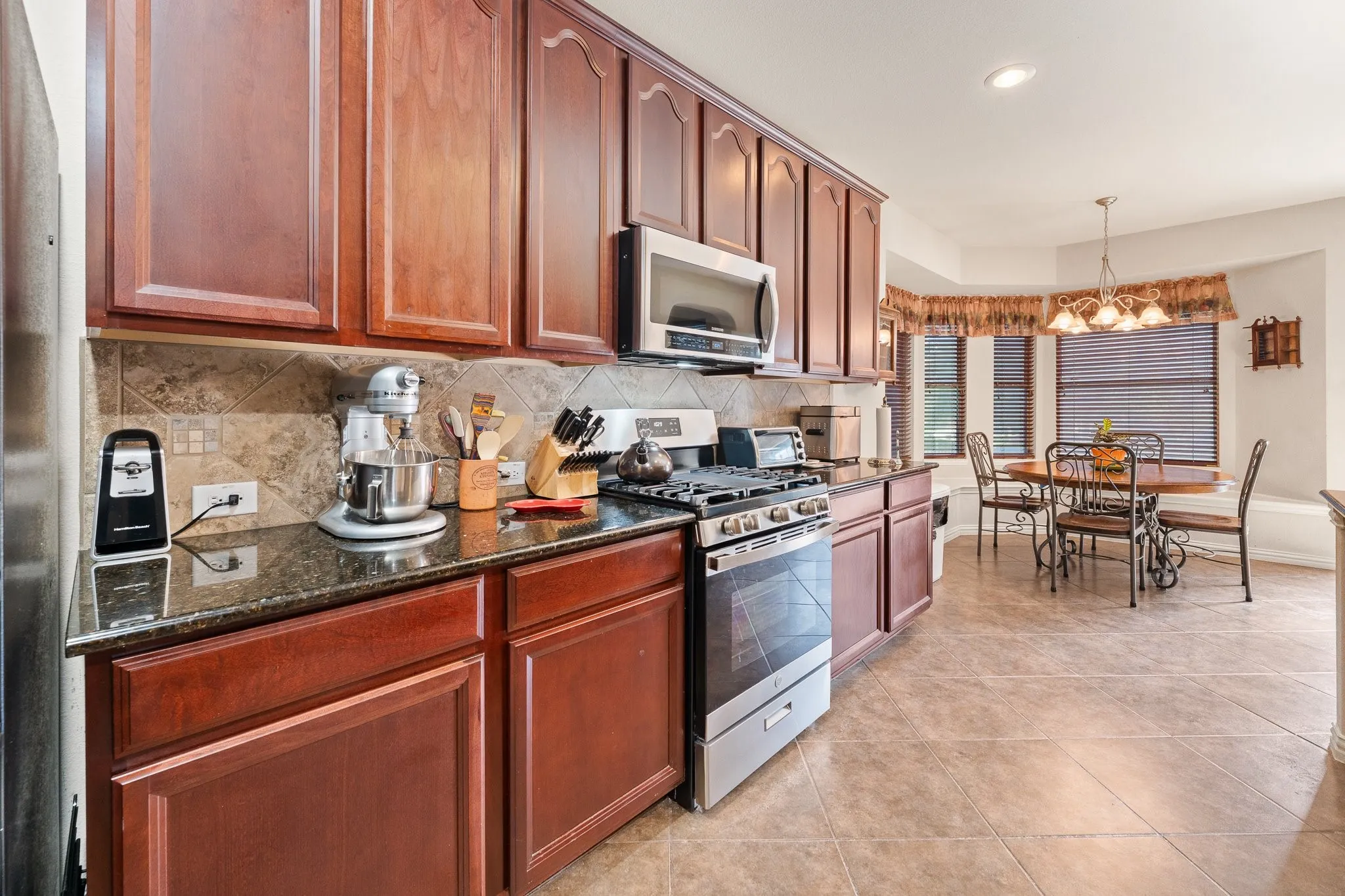 GAS RANGE, Microwave, wood cabinetry, granite countertops, and tile backsplash... OPENS to Breakfast Room Dining Area.