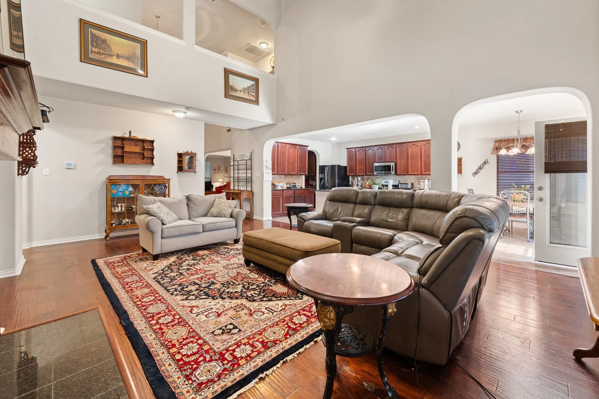 Open-concept Family Room OPENS to Kitchen featuring fireplace, soaring ceilings, wood flooring, and arched entryways.
