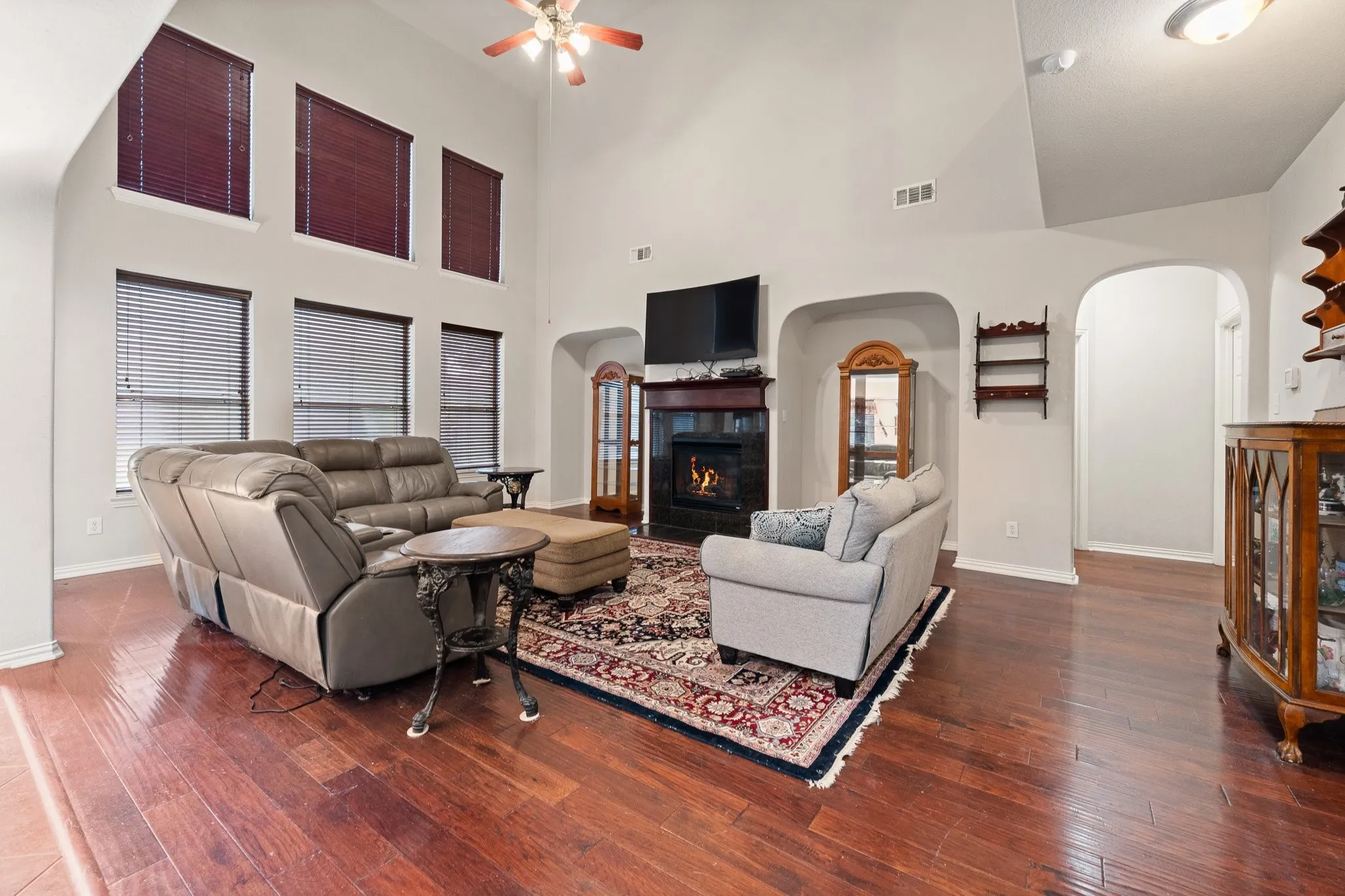 Family Room features vaulted ceiling, wood flooring, GAS LOGS Fireplace with a dark wood mantel, LOTS of Windows, and arched doorways.