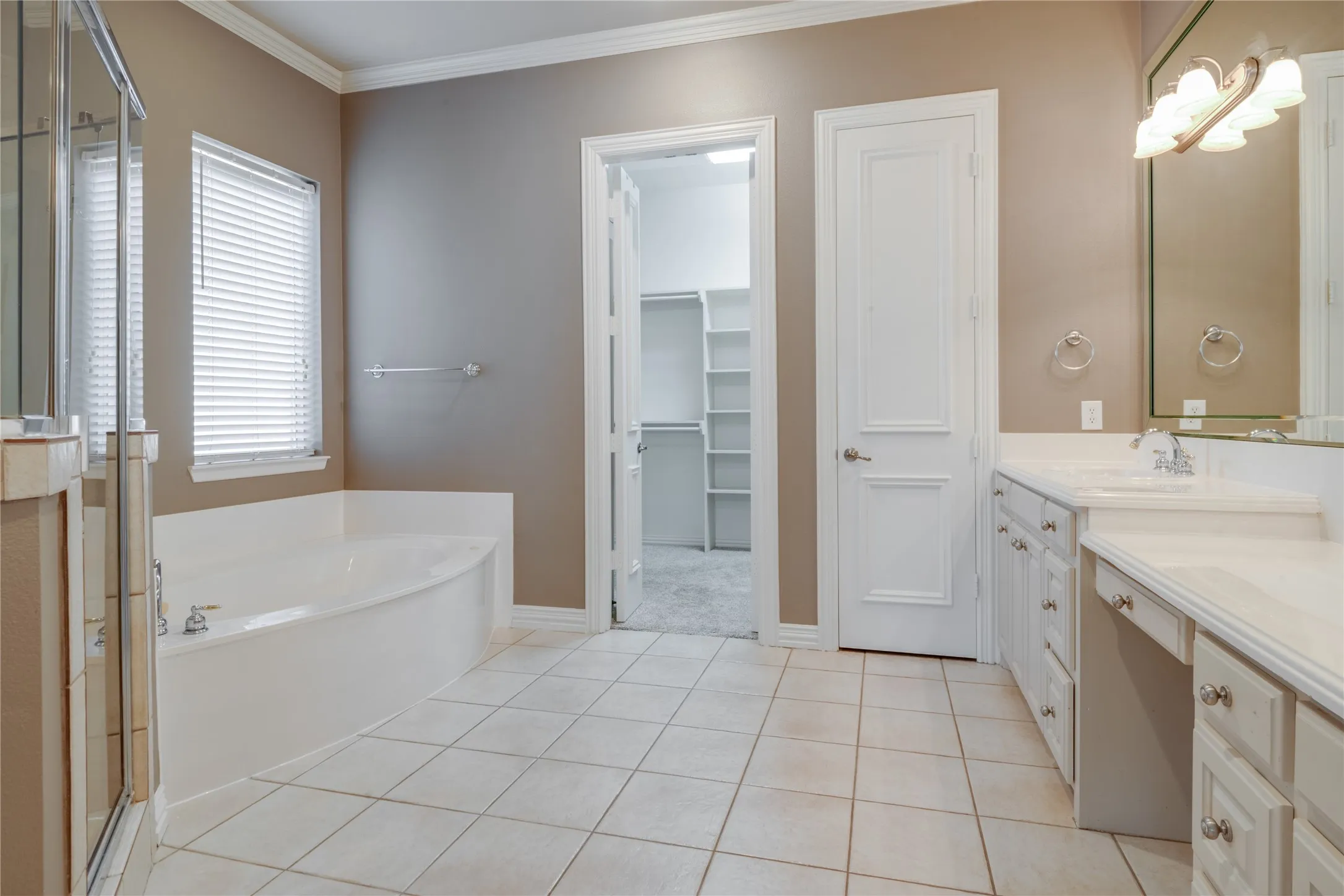 Expansive bathroom featuring a built-in soaking tub, a separate glass-enclosed shower, a double vanity with ample storage, and ceramic tile flooring