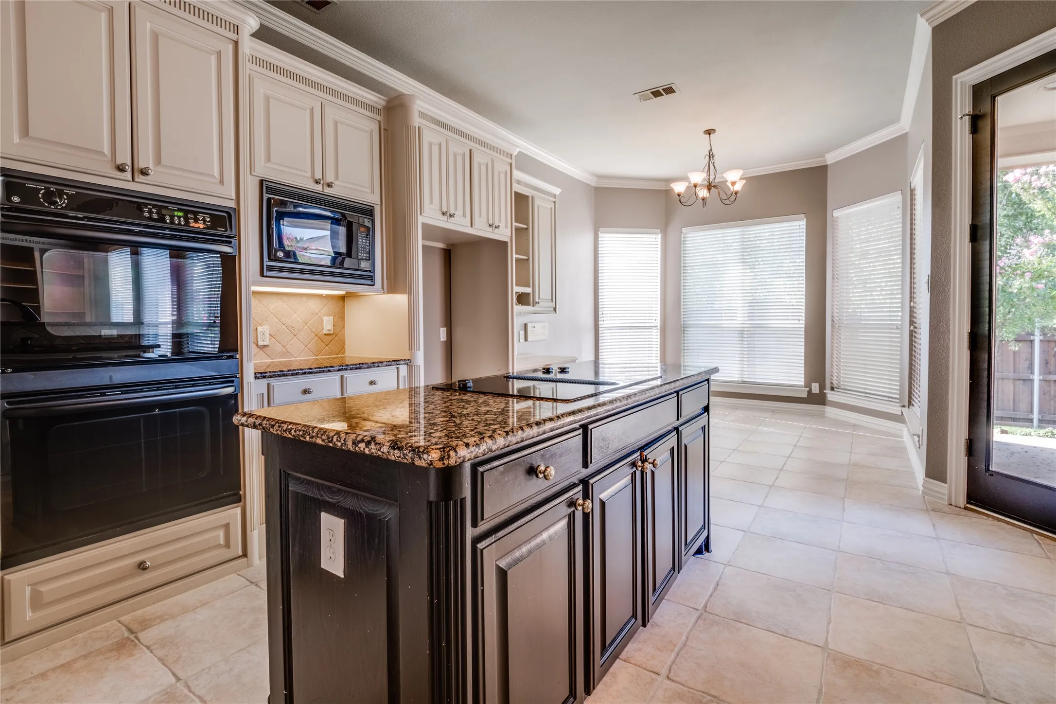 Kitchen featuring a built-in oven, microwave, a central island with an integrated cooktop, and tile flooring