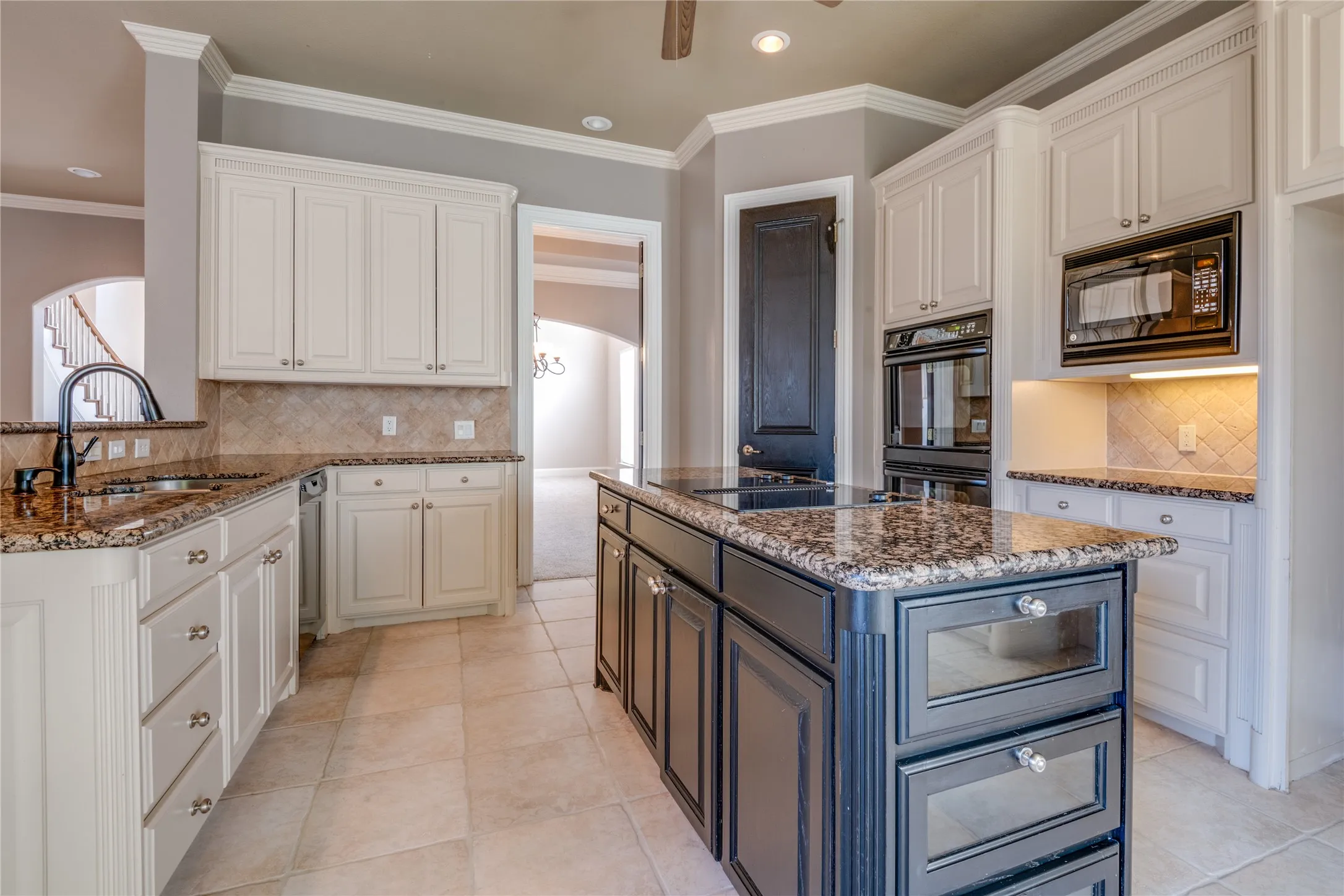 Kitchen featuring an island with built-in cooktop, double wall ovens, built-in microwave, and tile flooring