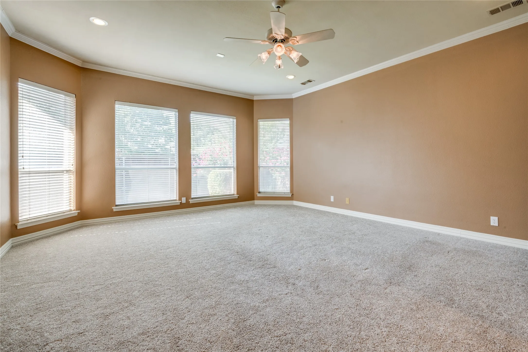 Spacious primary Bedroom featuring multiple windows, a ceiling fan, and recessed lighting