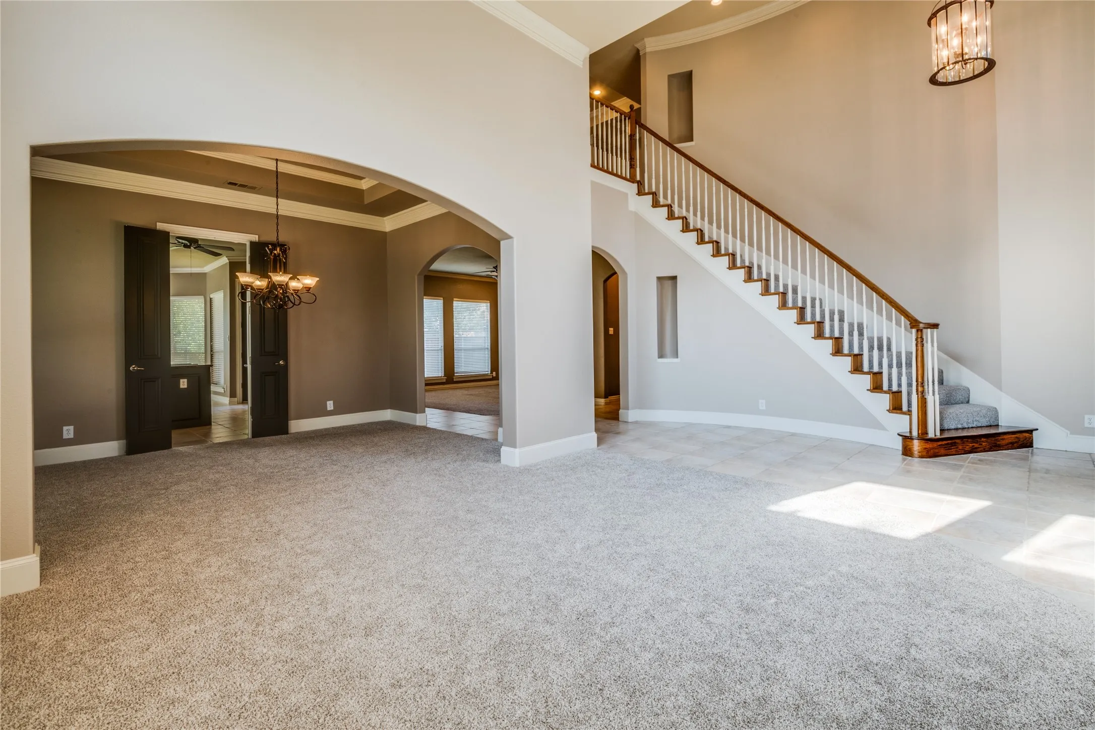 Entry with a grand staircase with wood treads and a white railing. Featuring The Dining area and front room.