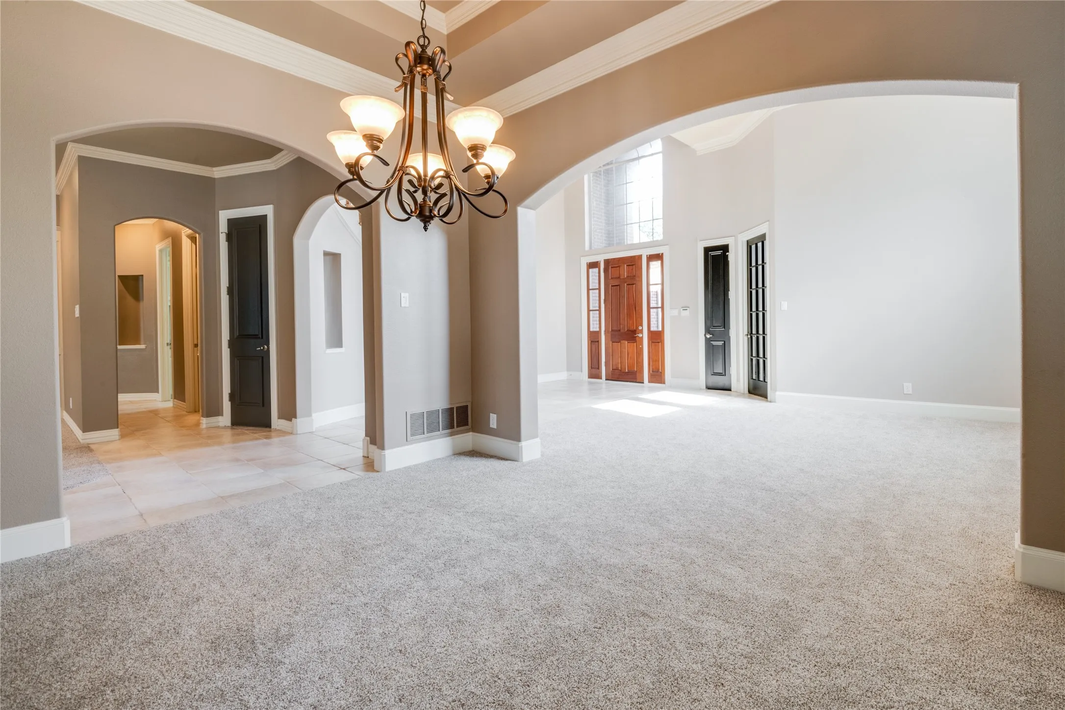 Dining Area Featuring Recessed ceiling with crown molding, double windows, decorative chandelier, and neutral carpeting