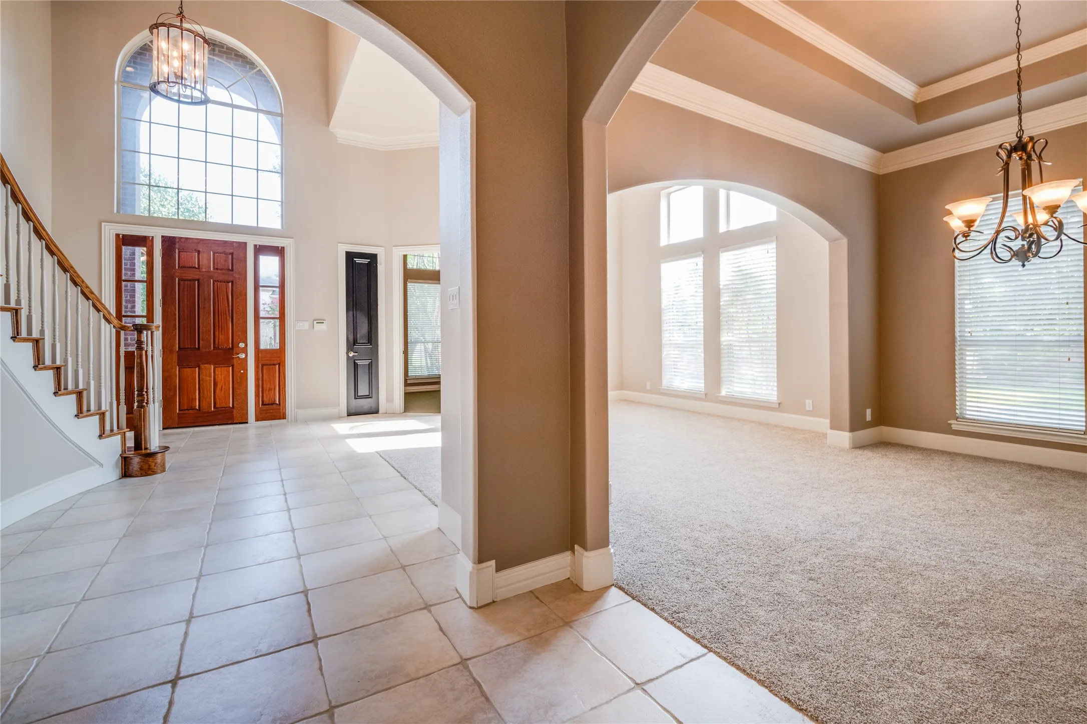 Two-story foyer with tile flooring, grand arched window, and a wood entry door. Featuring The Dining area and front room.