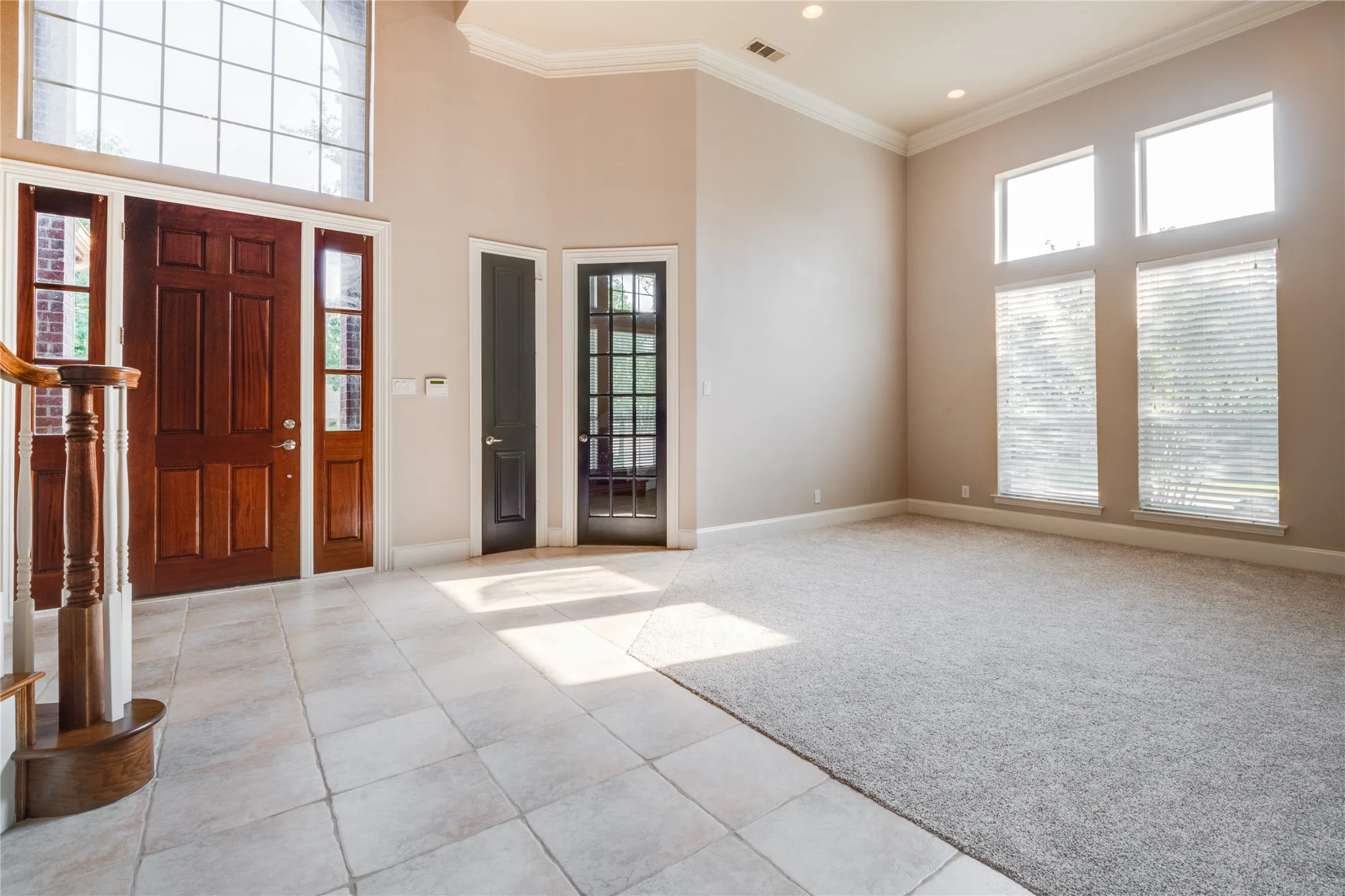 Two-story foyer with a solid wood entry door, side lights, and transom window