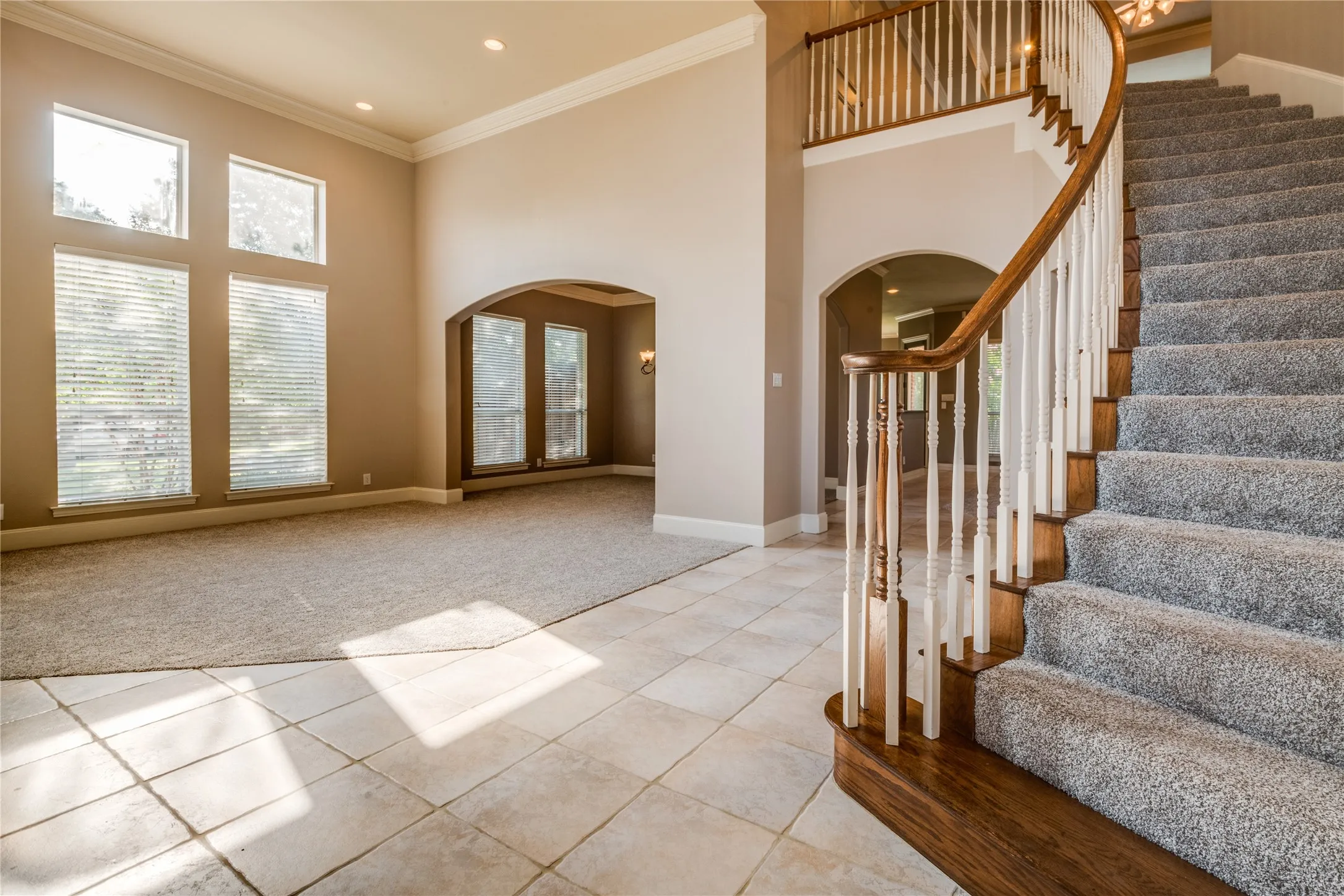 Entry with a grand staircase with wood treads and a white railing. Featuring The Dining area and front room.