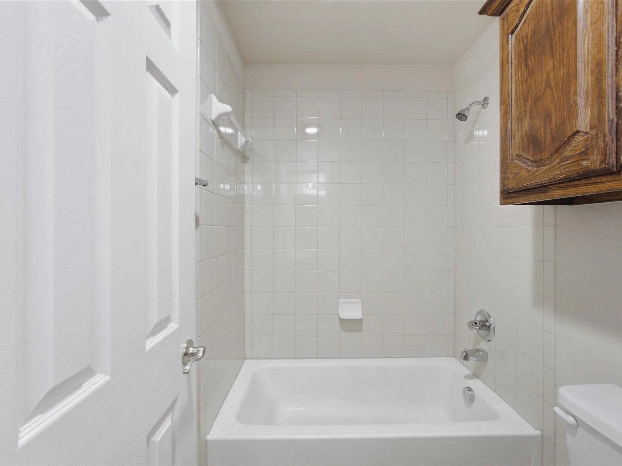 White subway tile shower surround with a built-in tub and chrome fixtures