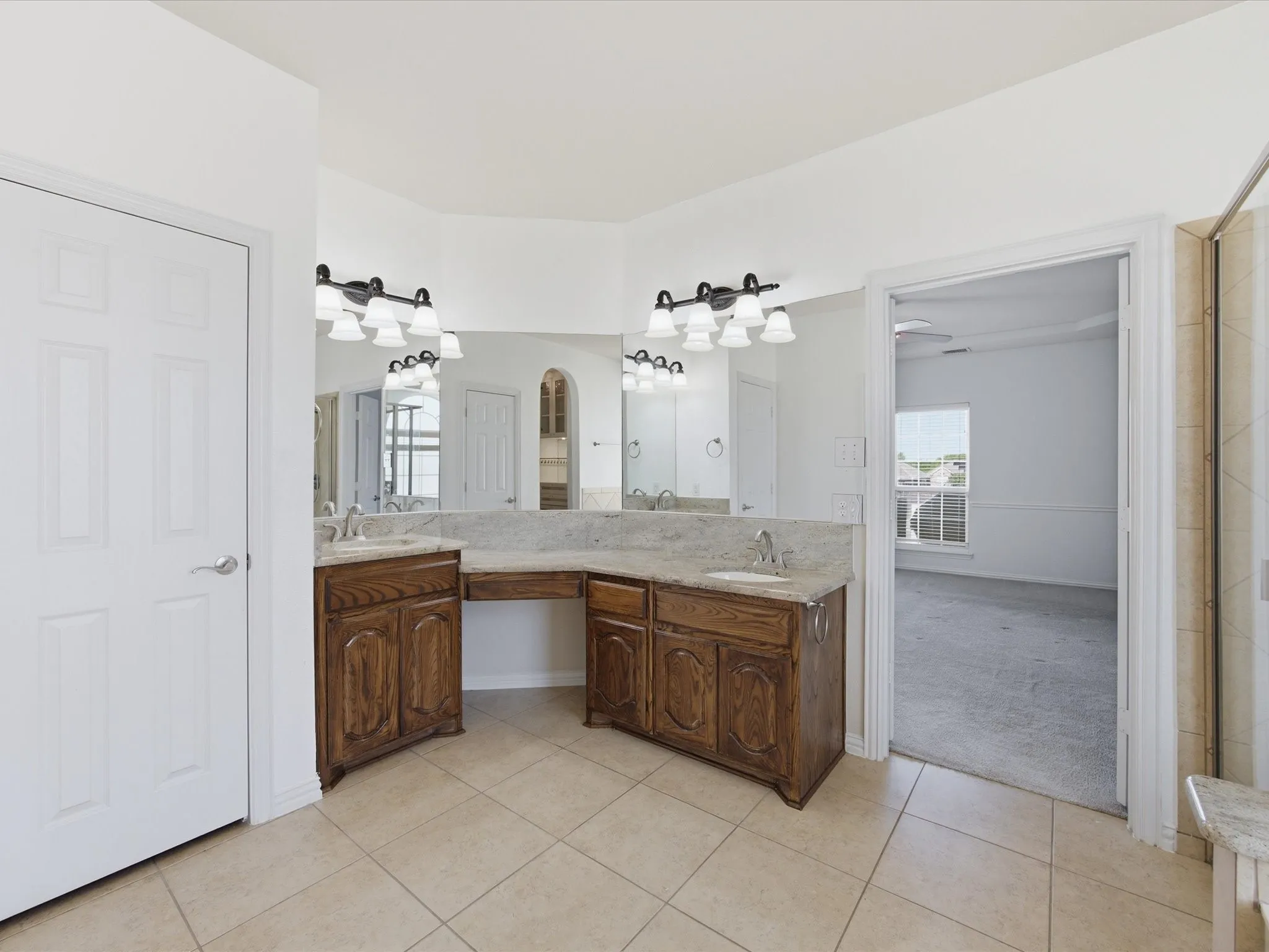 Dual vanity with integrated sinks, granite countertops, wood-finish cabinetry, and tile flooring