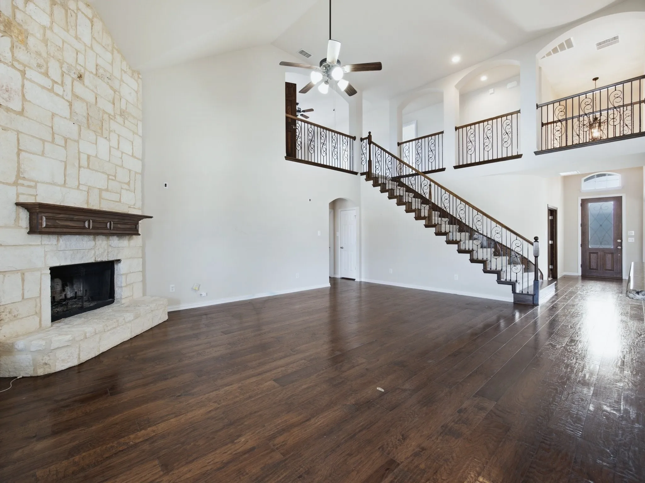 Soaring ceiling with a stone-clad fireplace and wood mantel