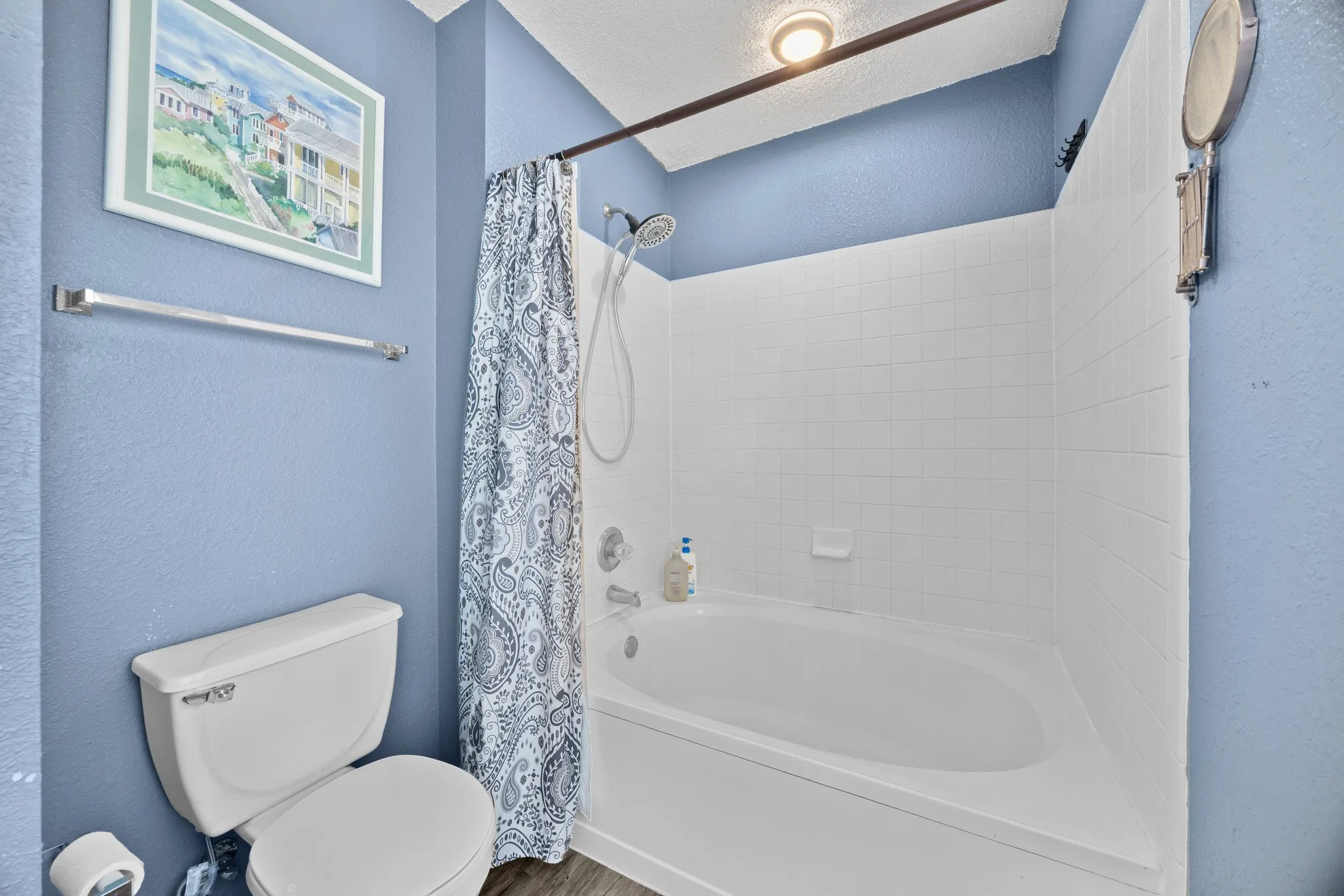 Bright, updated bathroom featuring crisp white subway tile surround, a deep soaking tub with shower combination, chrome fixtures, and soft blue accent walls