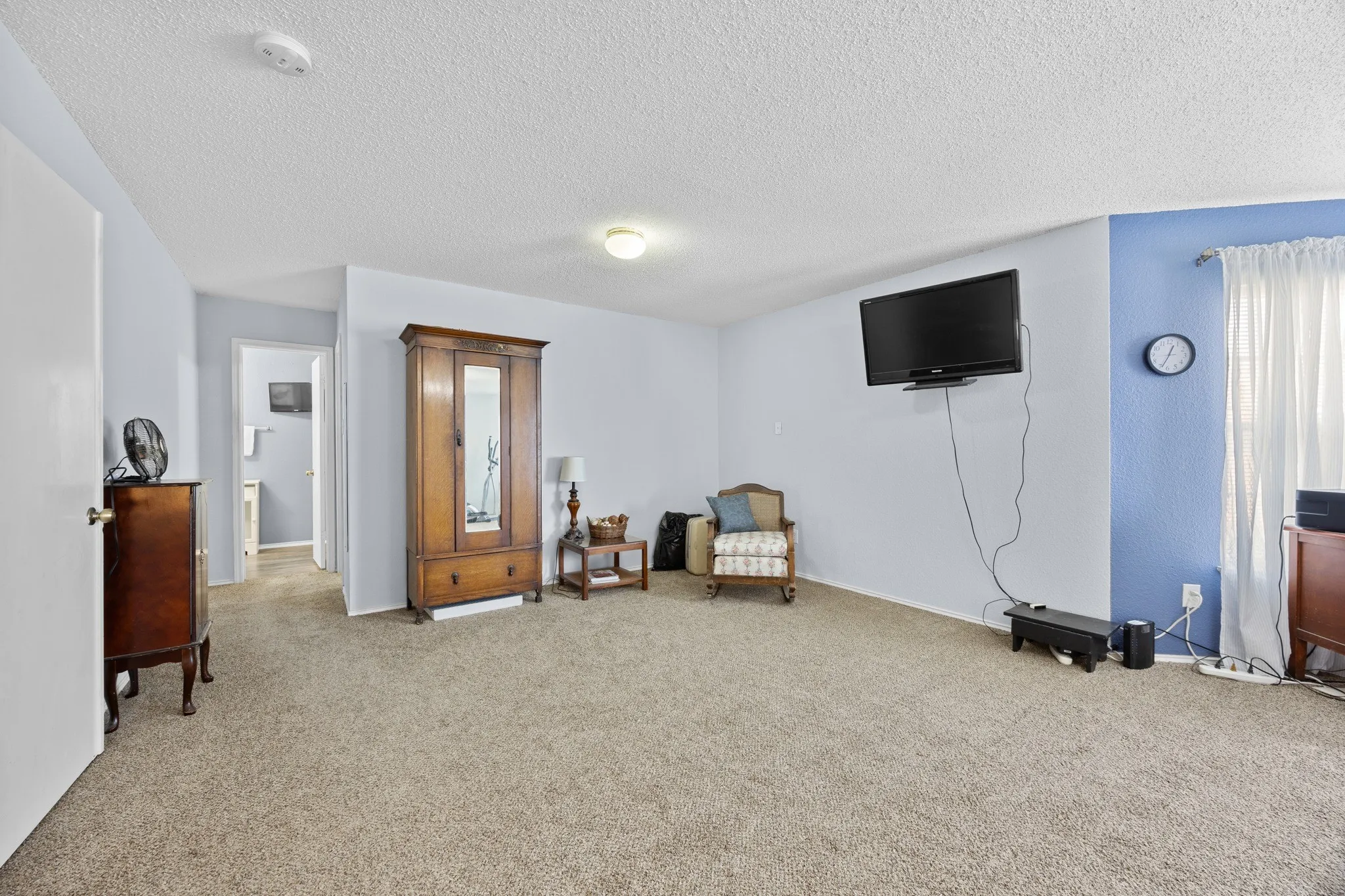 Carpeted room with light blue painted walls and a textured ceiling