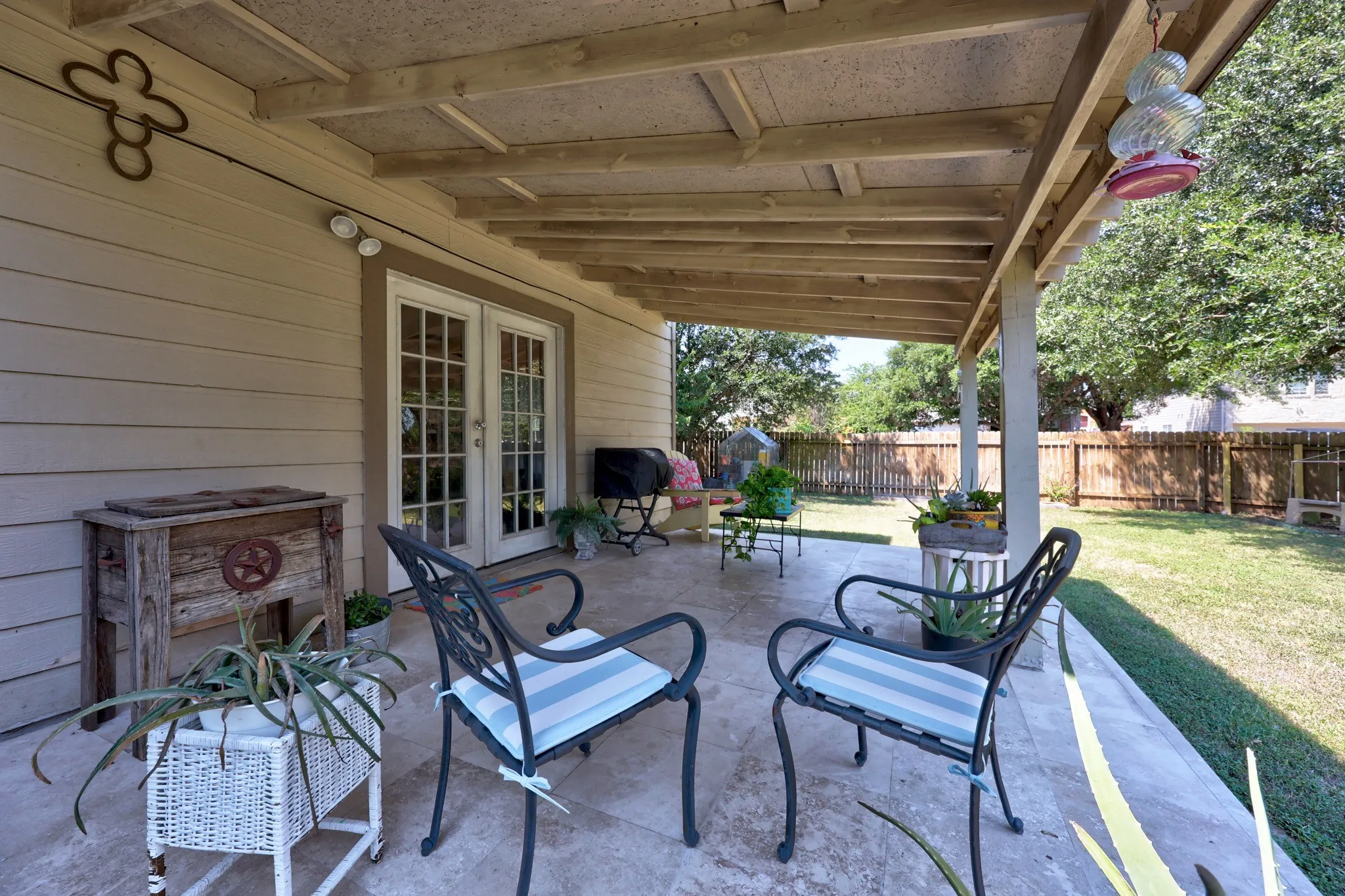 Covered patio with an exposed wood beam ceiling, French doors, and stone-finish flooring