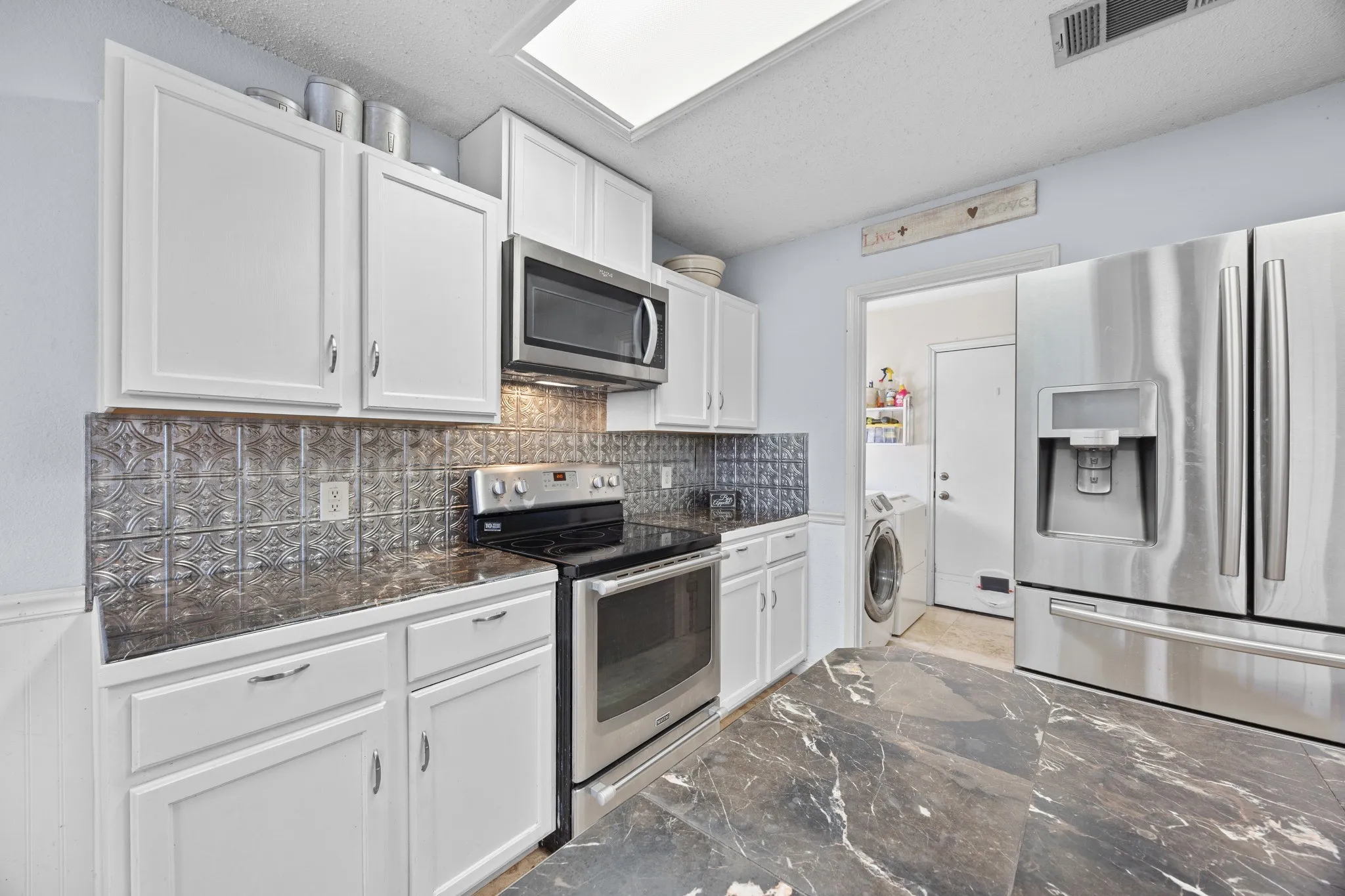 Kitchen featuring white cabinetry, dark stone-finish countertops, and a decorative tile backsplash