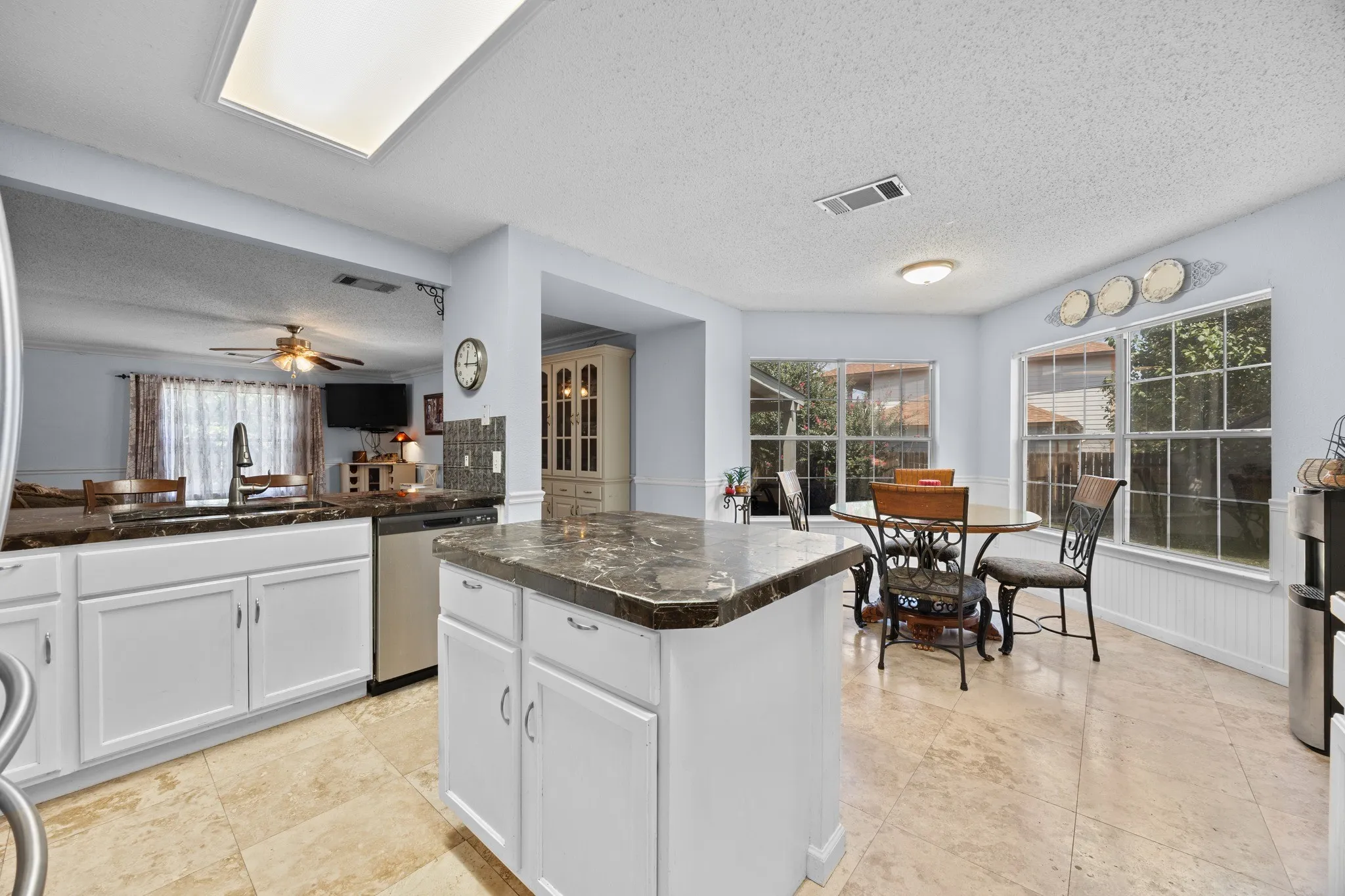 Kitchen featuring white cabinetry, dark stone countertops, tile flooring, and an integrated kitchen island