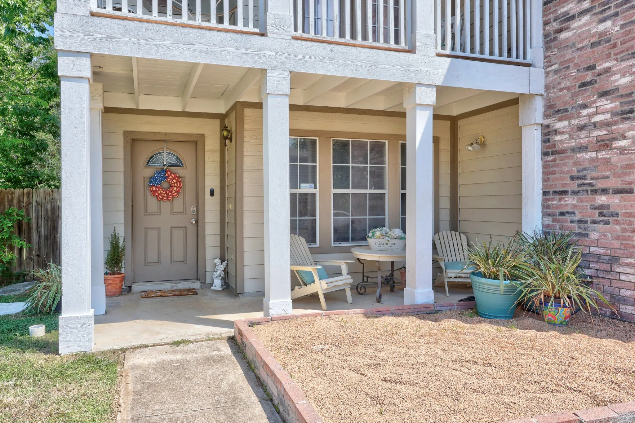 Covered porch entry with four support columns, brick facade, and horizontal siding